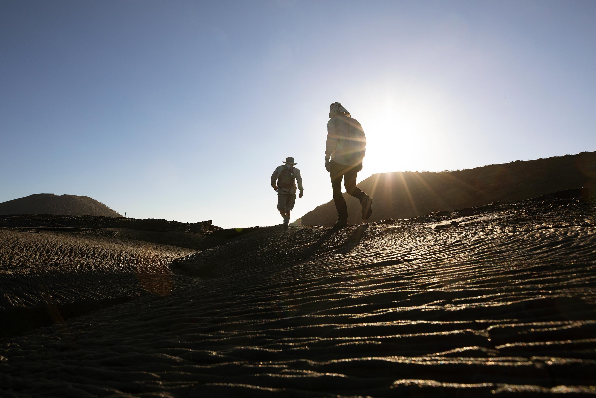 Sketchin - Case - Silversea Silver Origin Galapagos Islands - panoramic view, tho silhouette walking on solid lava, rock lava, igneous rock in the sunset 