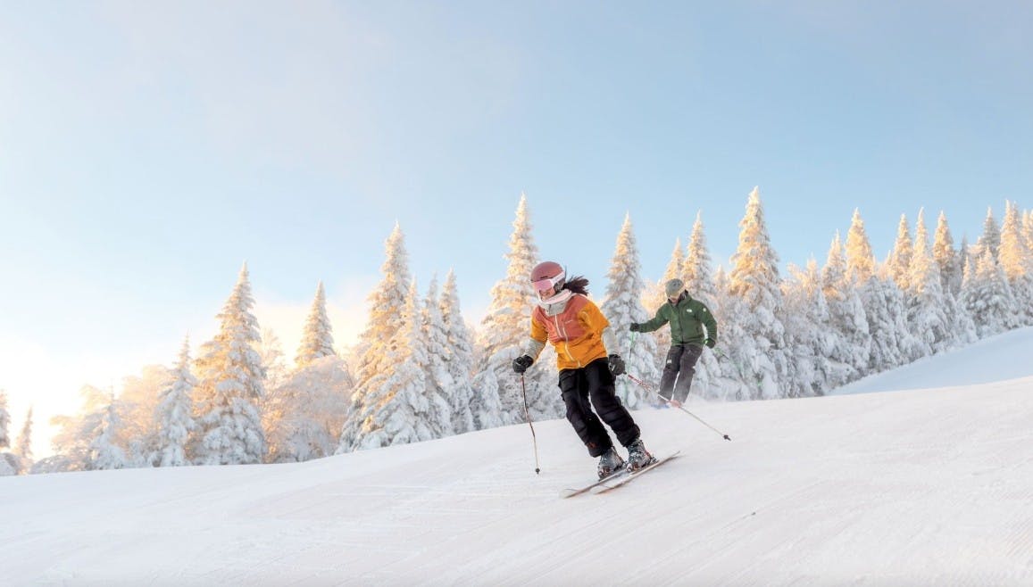 Two skiers skiing down a run at Mont Tremblant Resort on a sunny bluebird day