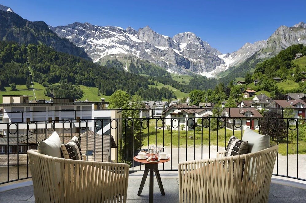 Two patio chairs sitting on a sunny patio overlooking the Swiss Alps at Kempinski Palace Engelberg