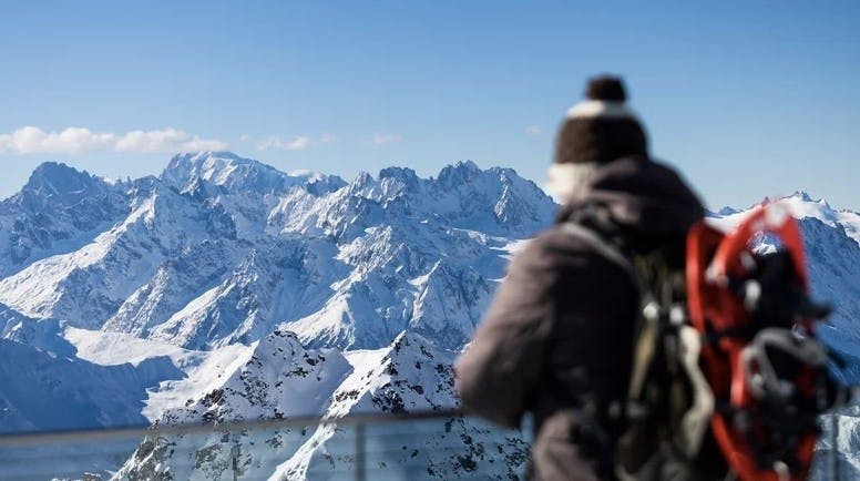 Snowshoer standing on a balcony overlooking the Swiss Alps at Verbier