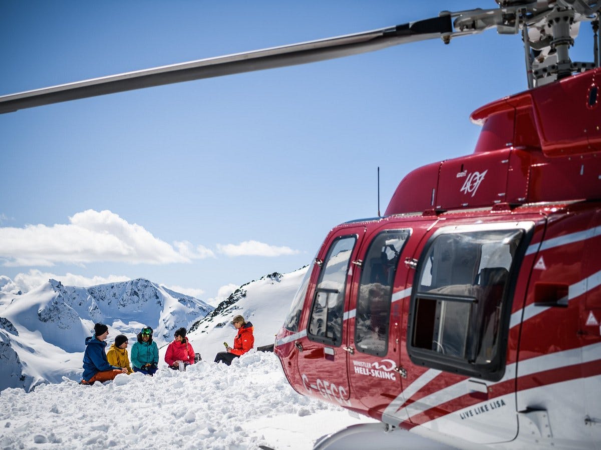 Skiers resting on the summit before their helicopter takes off in Whistler Blackcomb in British Columbia, Canada.