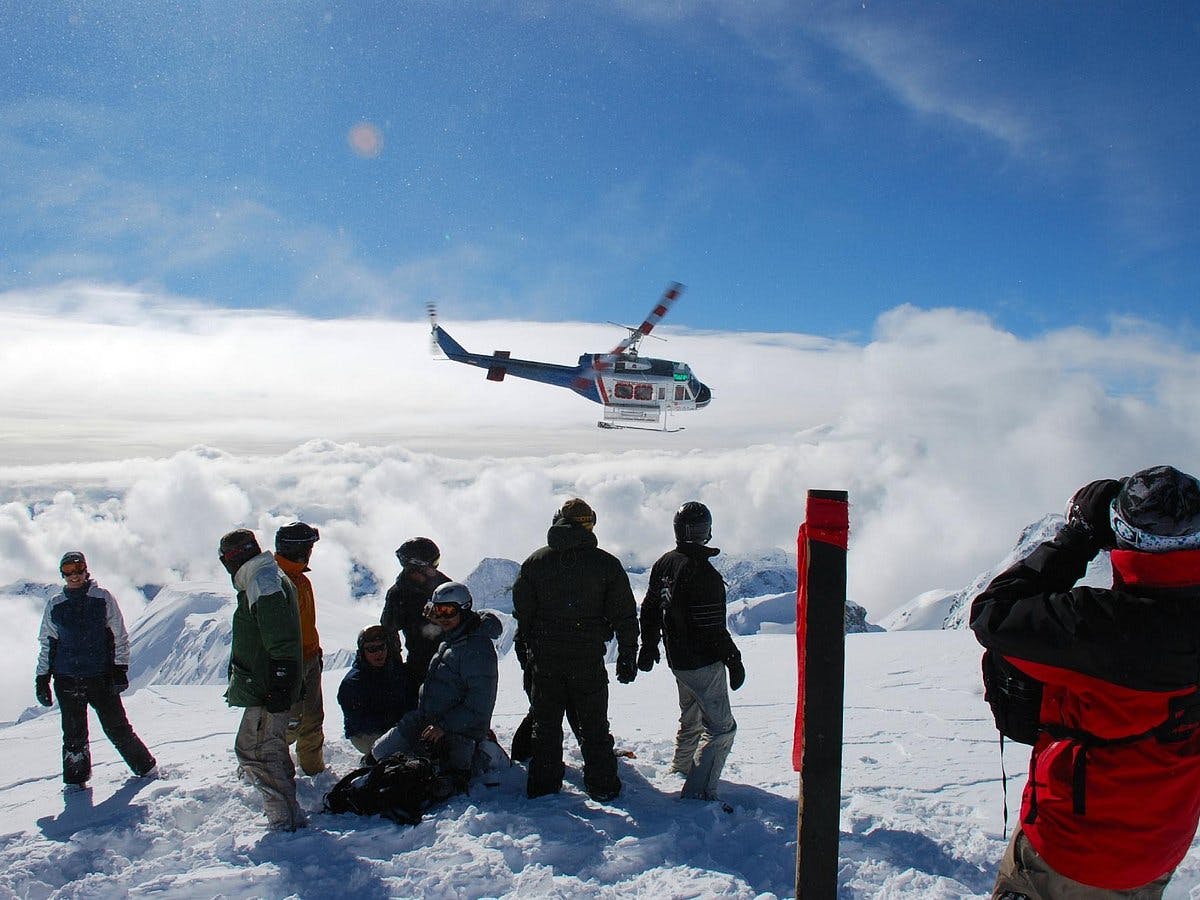 Helicopter taking off as skiers prepare to make their descent in Whistler Blackcomb in British Columbia, Canada.