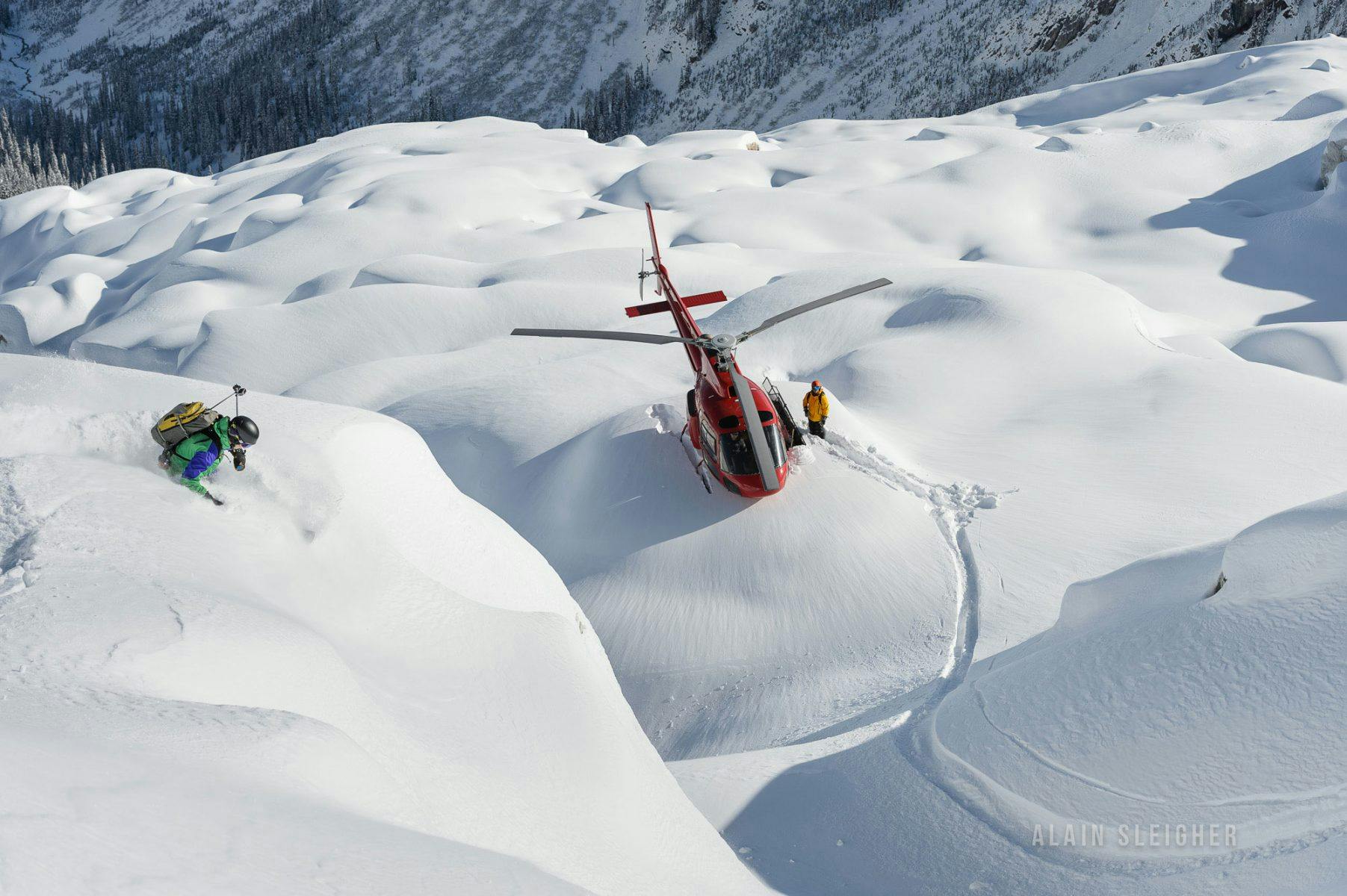 Skiers making their way to the helicopter amidst deep snow on the slopes of Revelstoke in British Columbia, Canada.