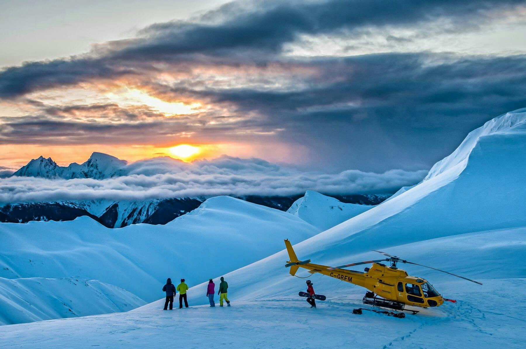 Skiers at the summit next to their helicopter operated by Last Frontier Heli-skiing in Revelstoke in British Columbia, Canada.