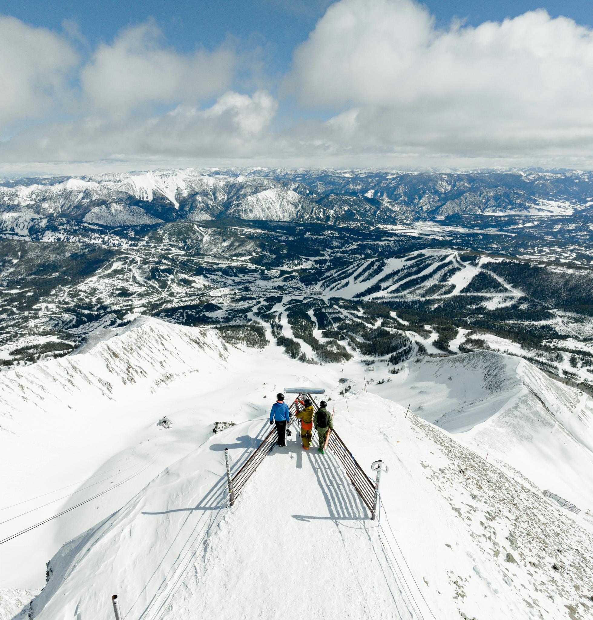 three skiers stand at the top of Lone Peak at Big Sky in Montana, USA.