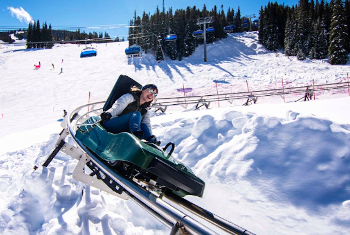 smiling kid riding the Rocky Mountain Coaster at Copper Ski Resort on a sunny day