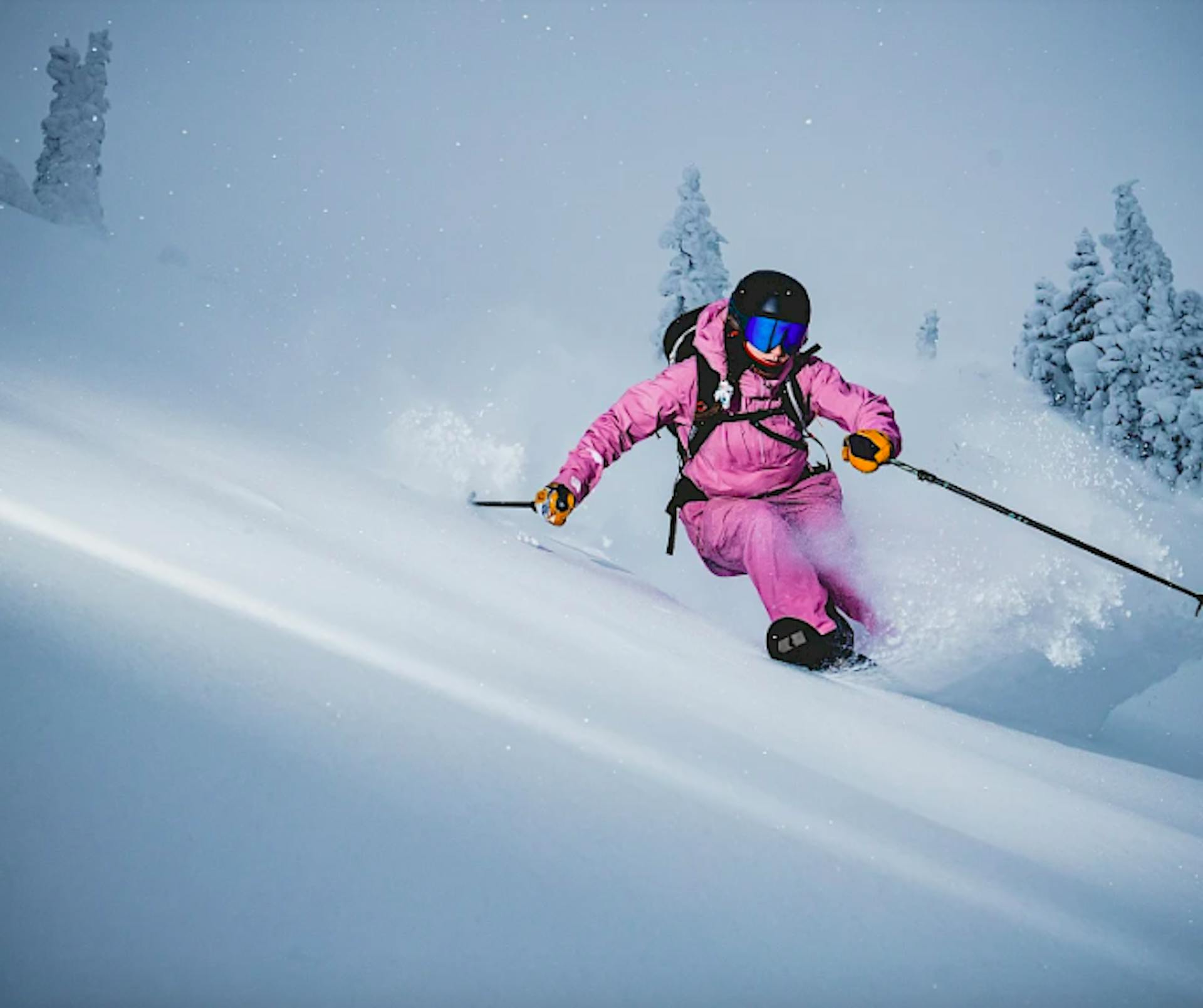 skier in pink jumpsuit skiing down powder runs in Revelstoke British Columbia