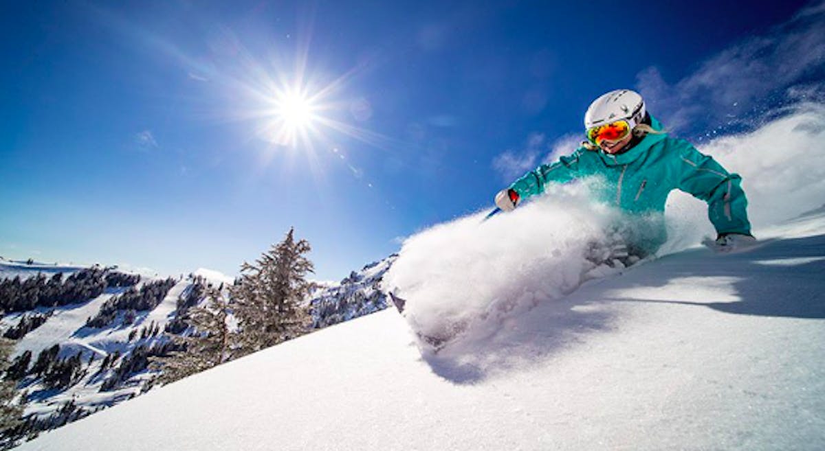 snowboarder shredding the slopes on a sunny day at Palisades Tahoe