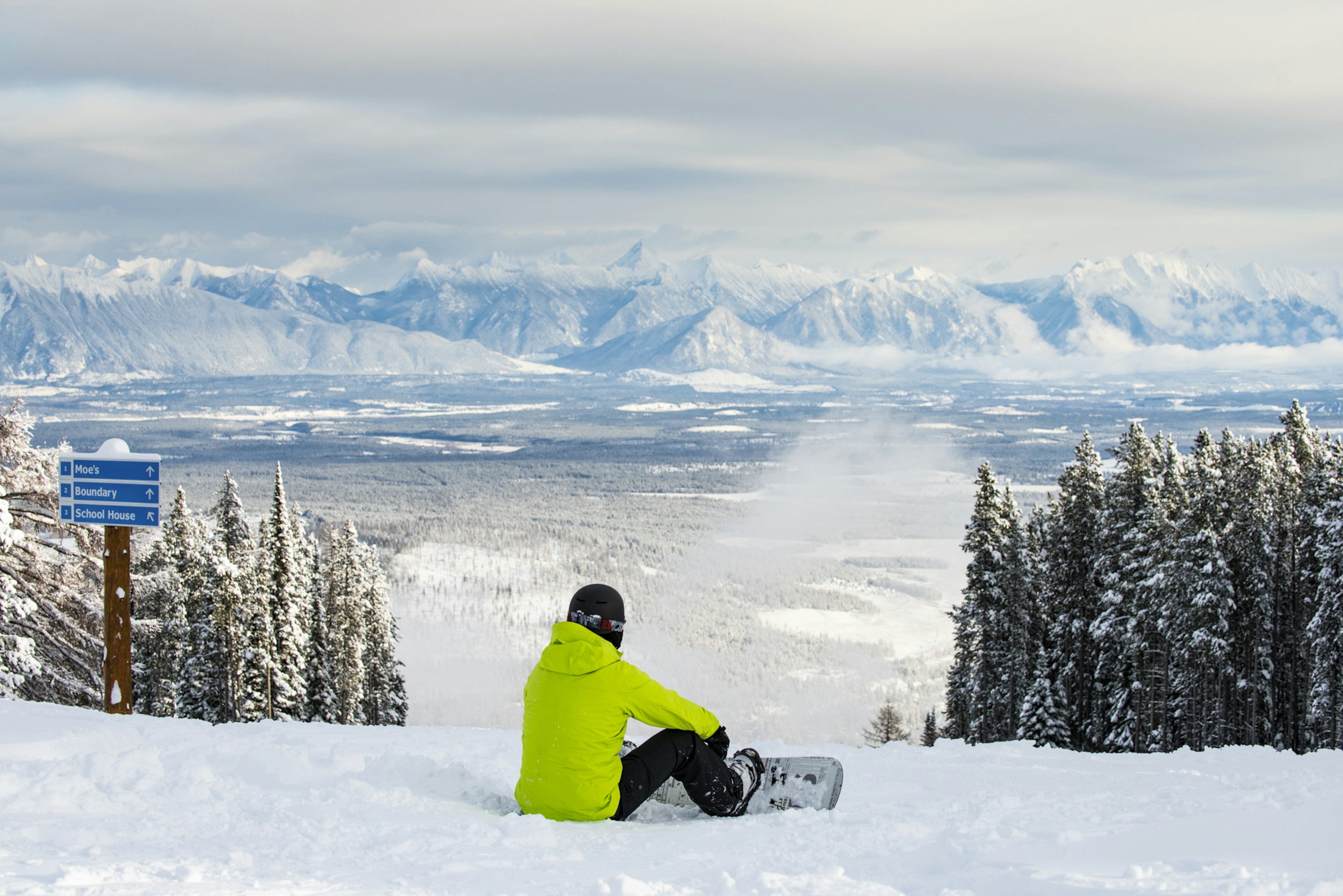 Skier of undiscernible gender in yellow ski jacket scanning the horizon at Kimberley Alpine Resort in Kimberley, British Columbia, Canada.