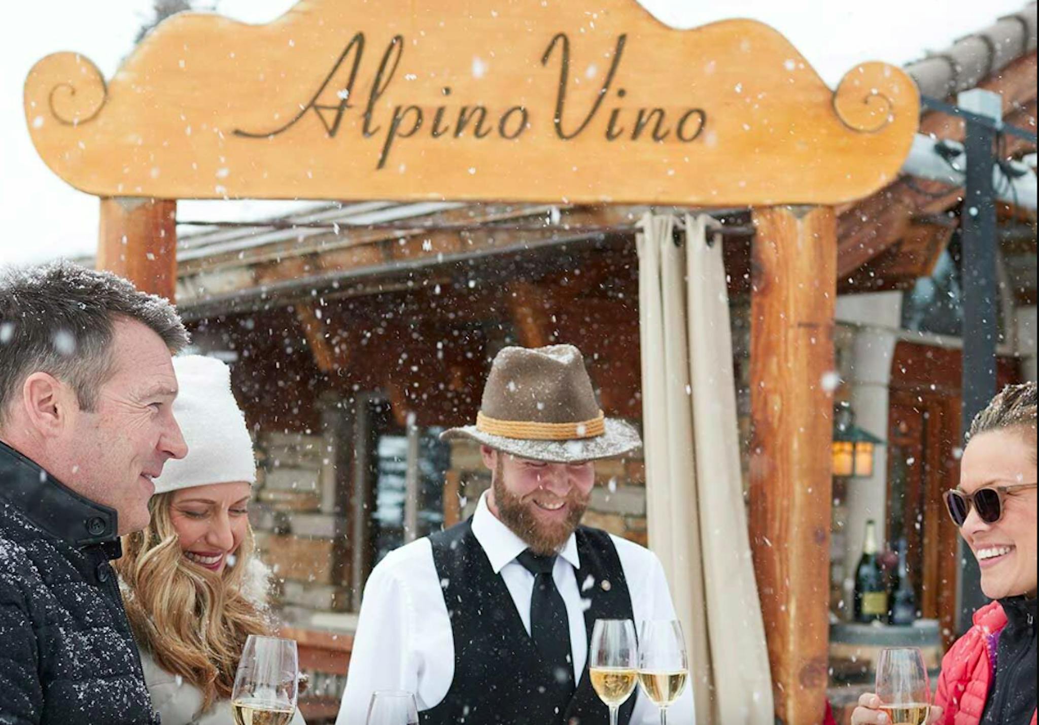 couple enjoying champagne in the falling snow outside Alpino Vino