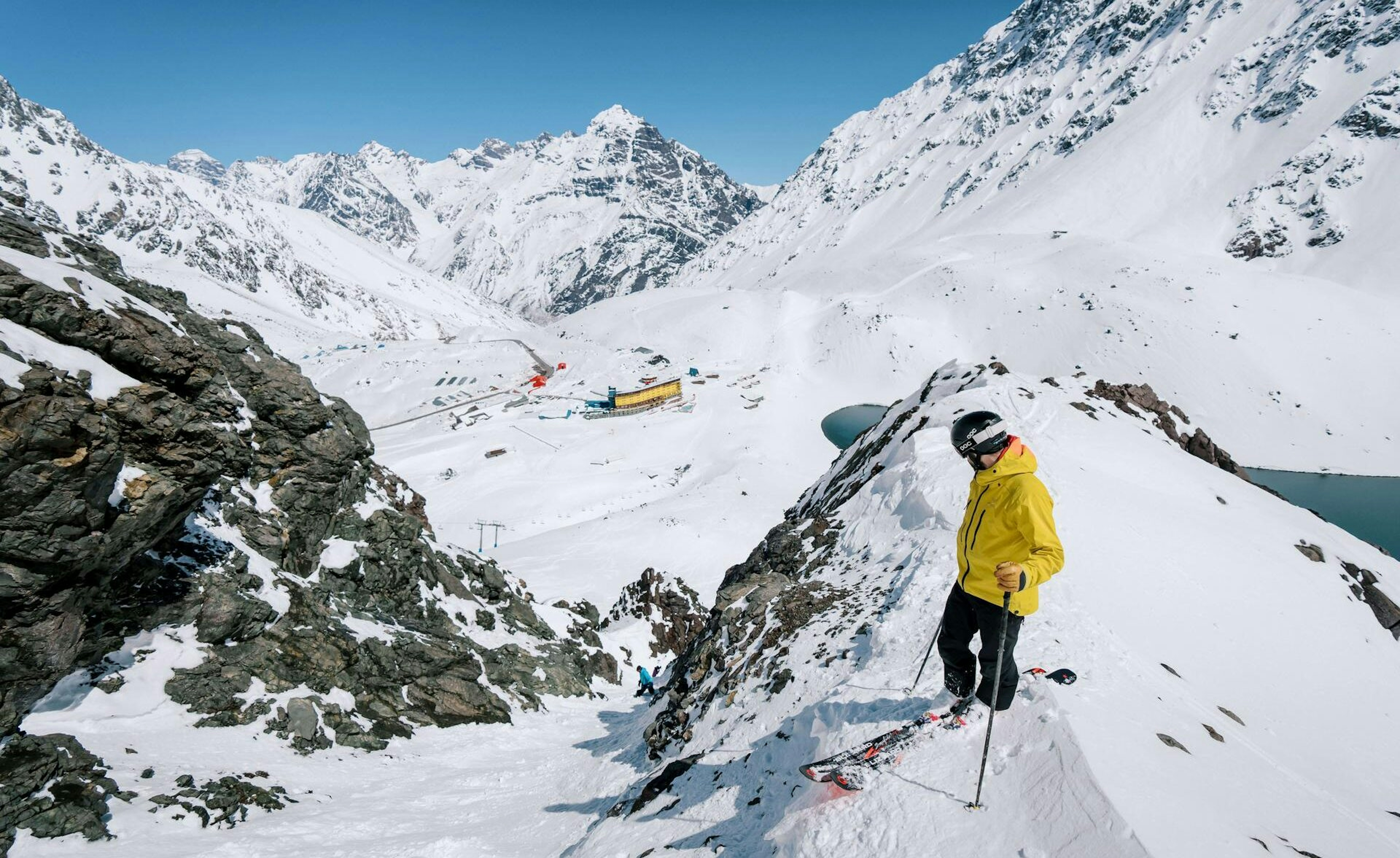 Male skier in yellow ski jacket admiring the peak at Portillo in Chile, South America.