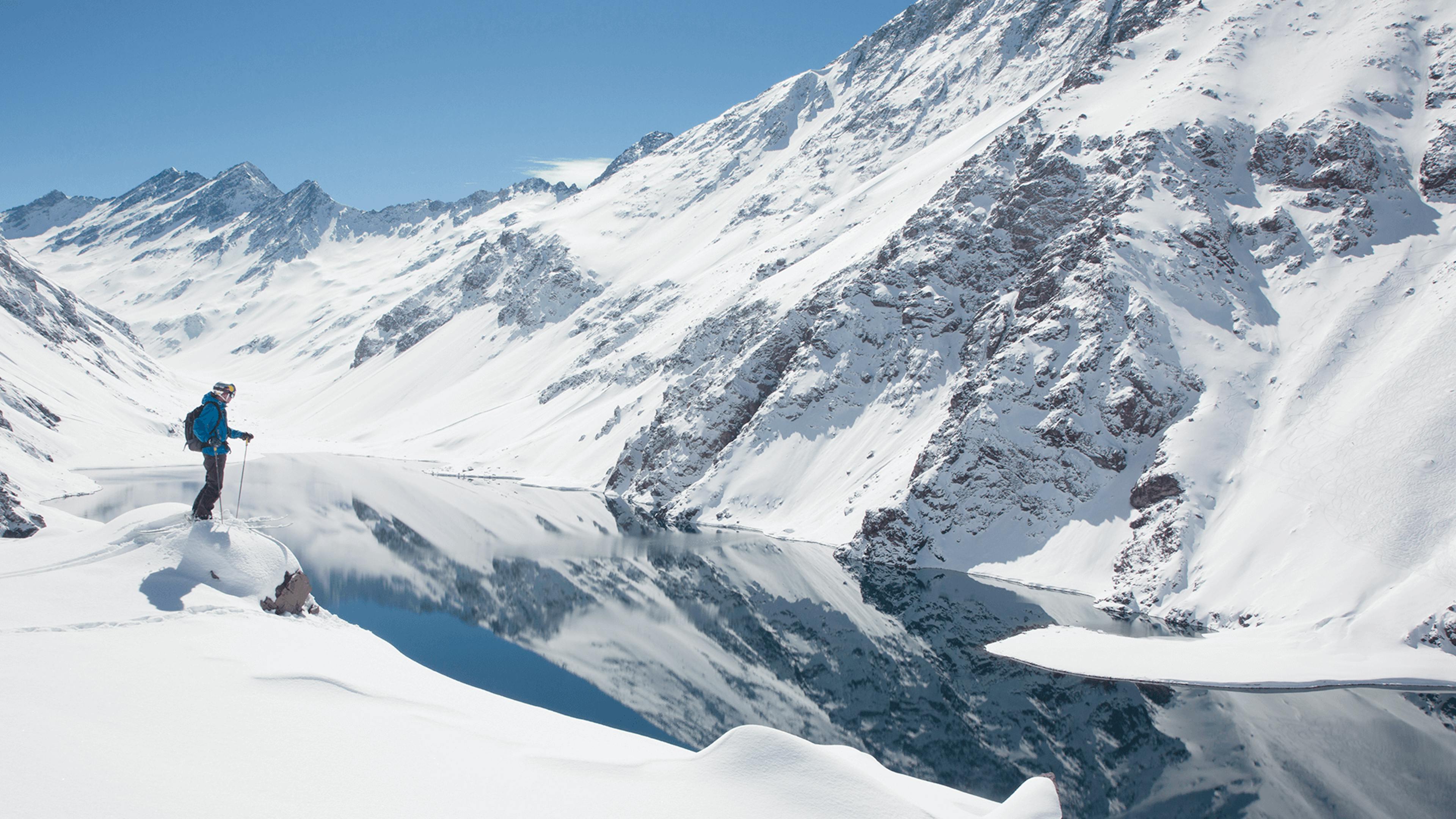 A skier of undiscernible gender in blue ski jacket enjoying back-country skiing at Portillo in Chile, South America.