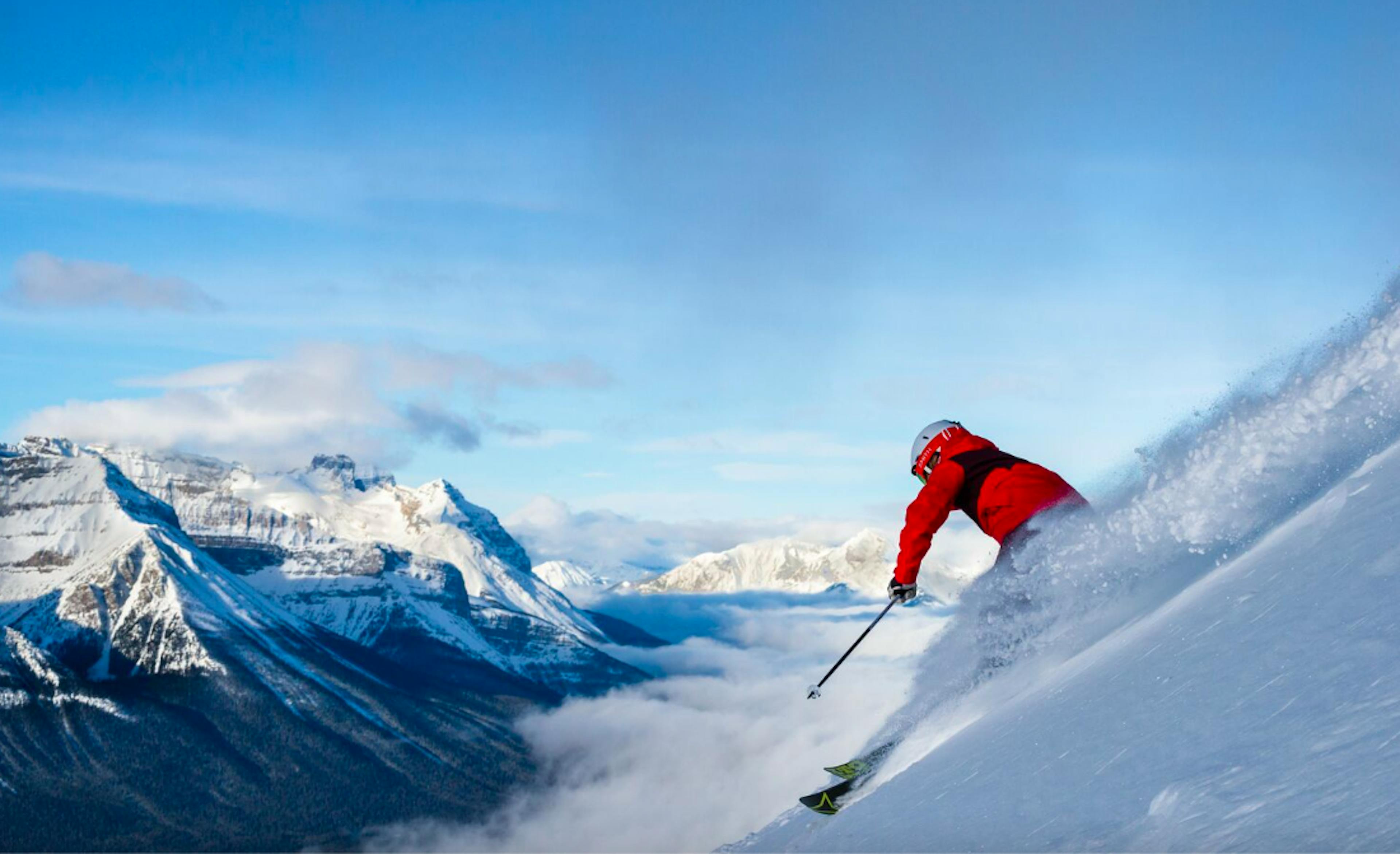 Skier in red jumpsuit skiing down a steep run at Banff Lake Louise