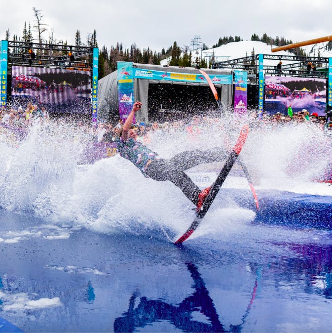 skier flailing as they skim a water pond at Banff Sunshine Slush Cup