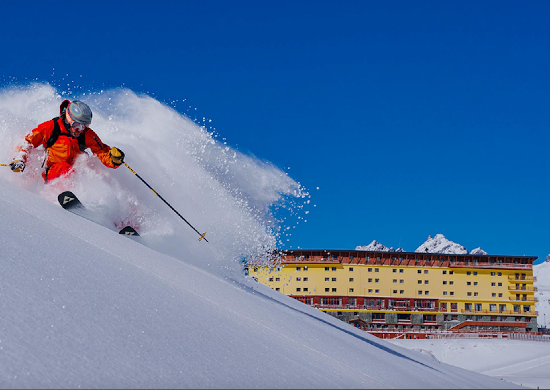 skier in red jumpsuit spraying powder on the slopes of Portillo Chile ski resort