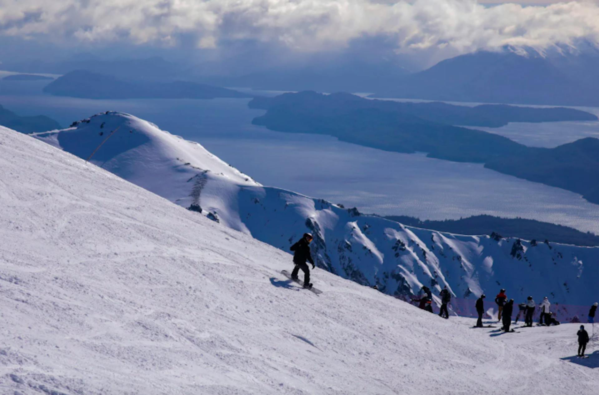 riders on a snowy slope overlooking lakes and mountains at Cerro Catedral ski resort