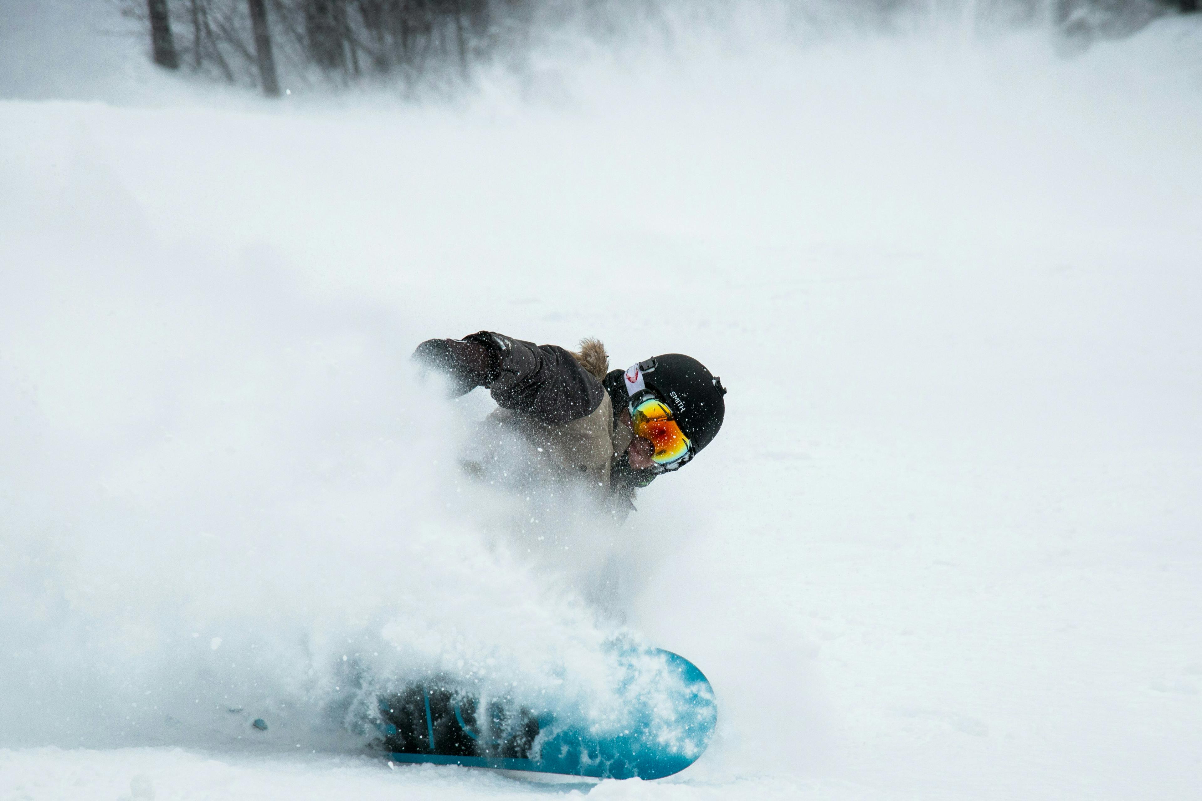 snowboarder riding powder on a snowy slope