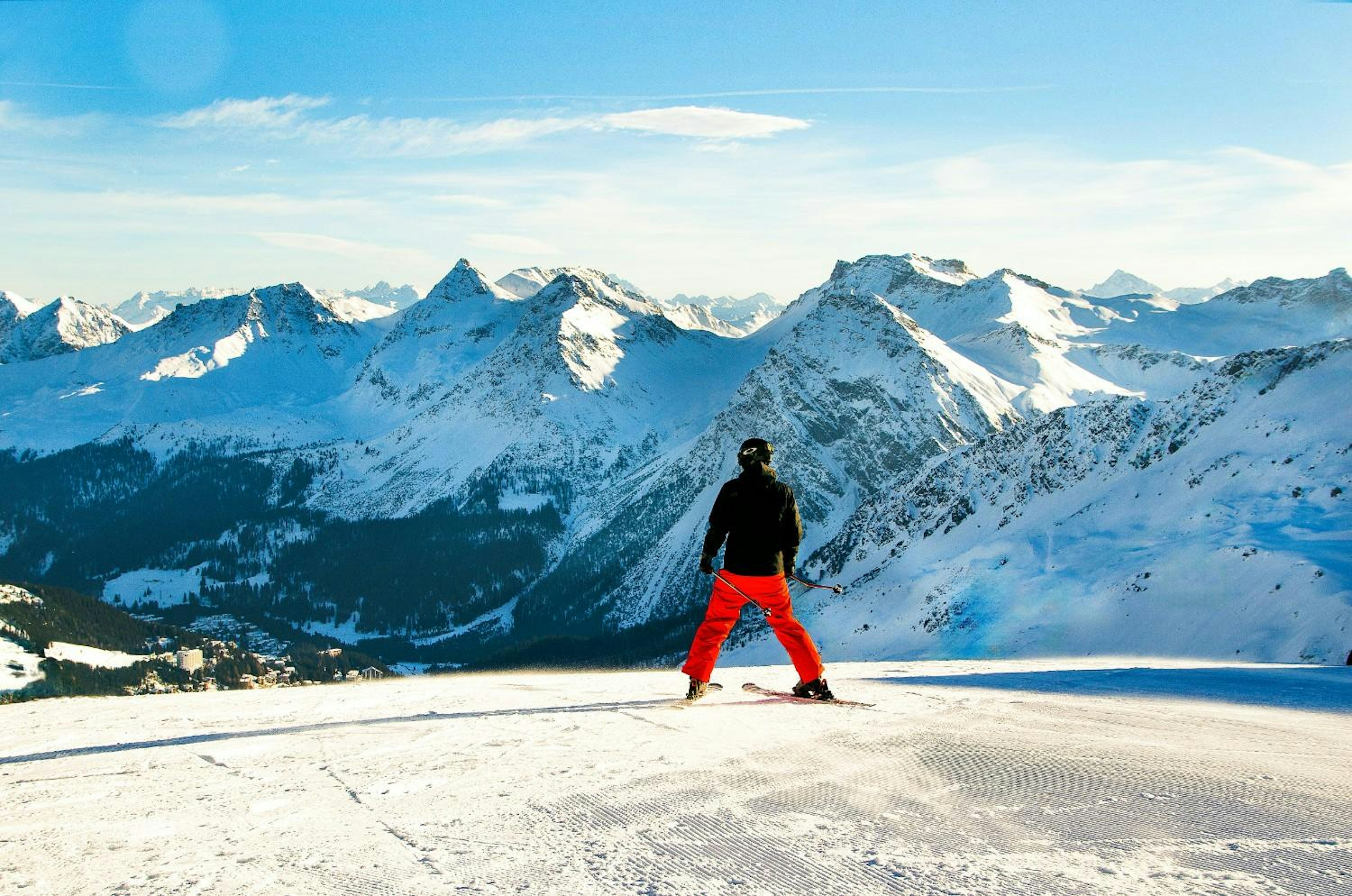 a beginner sker stands at the top of a slope at a mountain range in europe