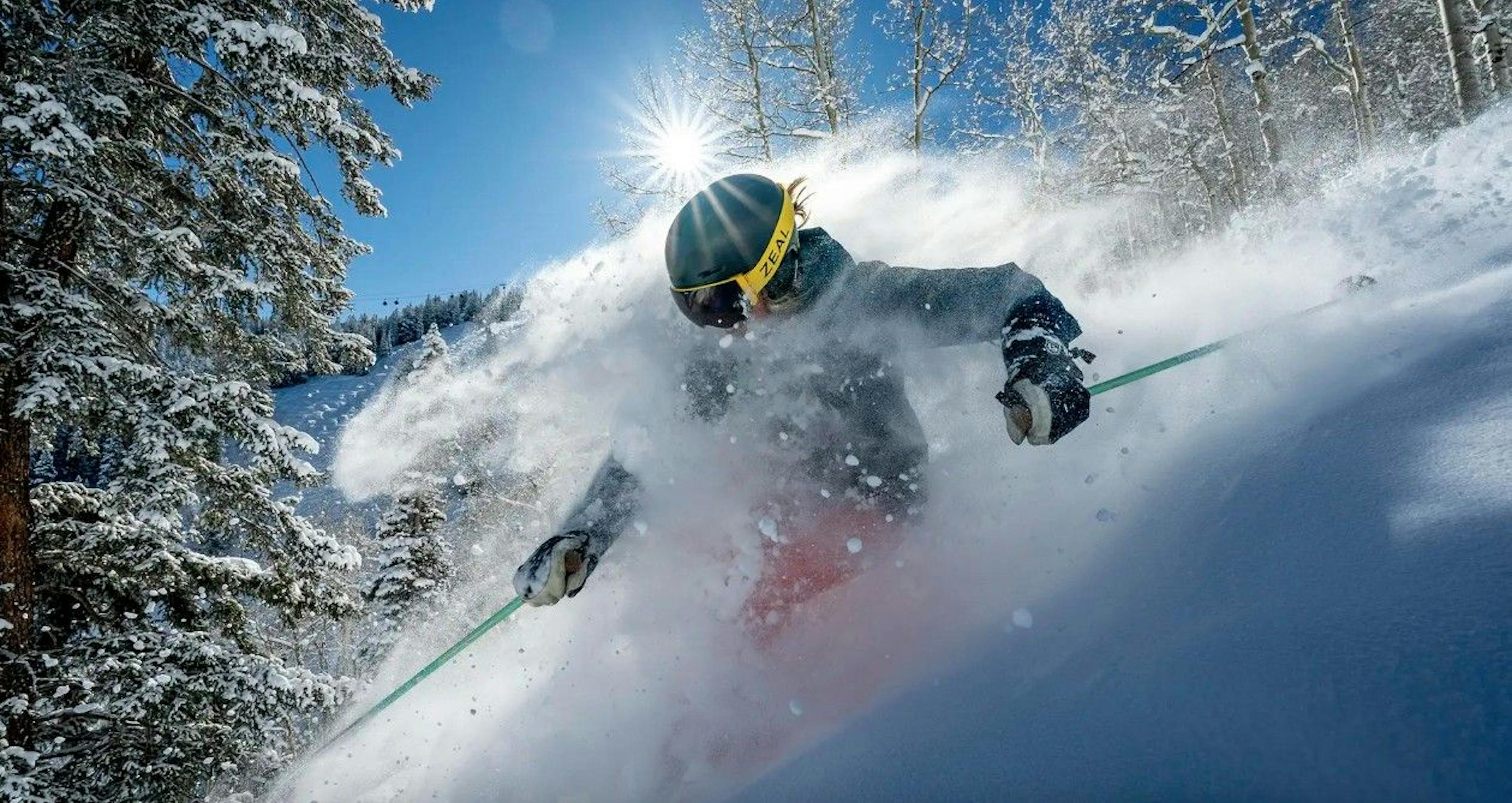 Skiier spraying powder on a sunny ski slope in Aspen