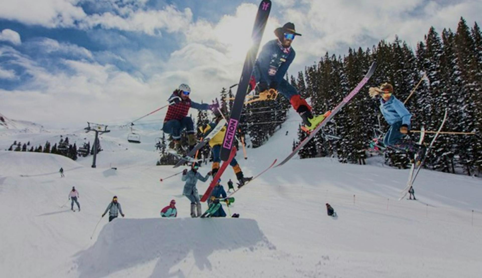 Several skiers doing tricks in the air at the Arapahoe Basin terrain park on a sunny day