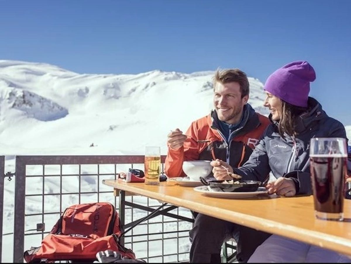 smiling couple eating and drinking on a sunny patio at St. Anton, Austria Ski Reosrt