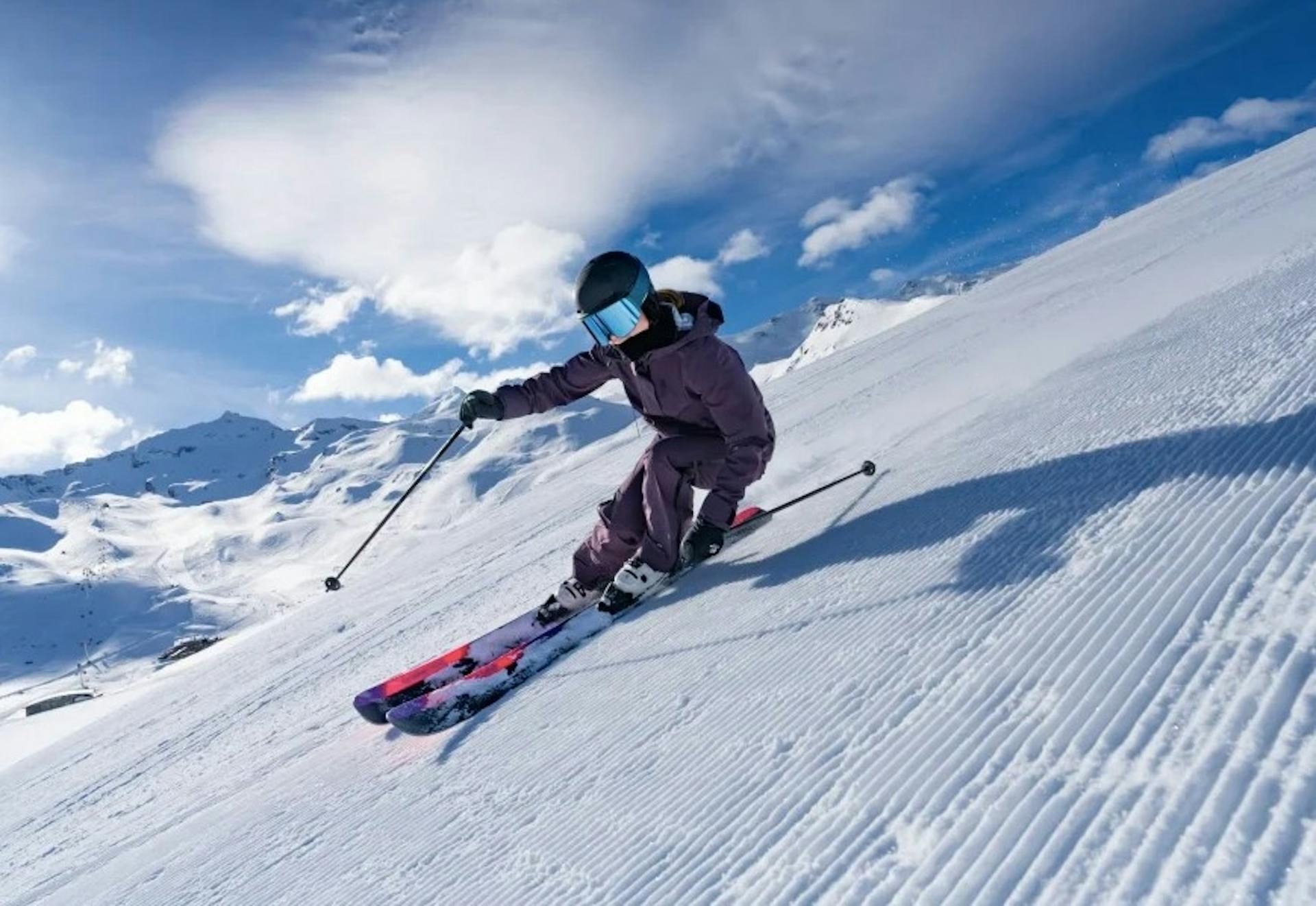 skier enjoying a sunny day on a groomed slope at Val Thorens ski resort