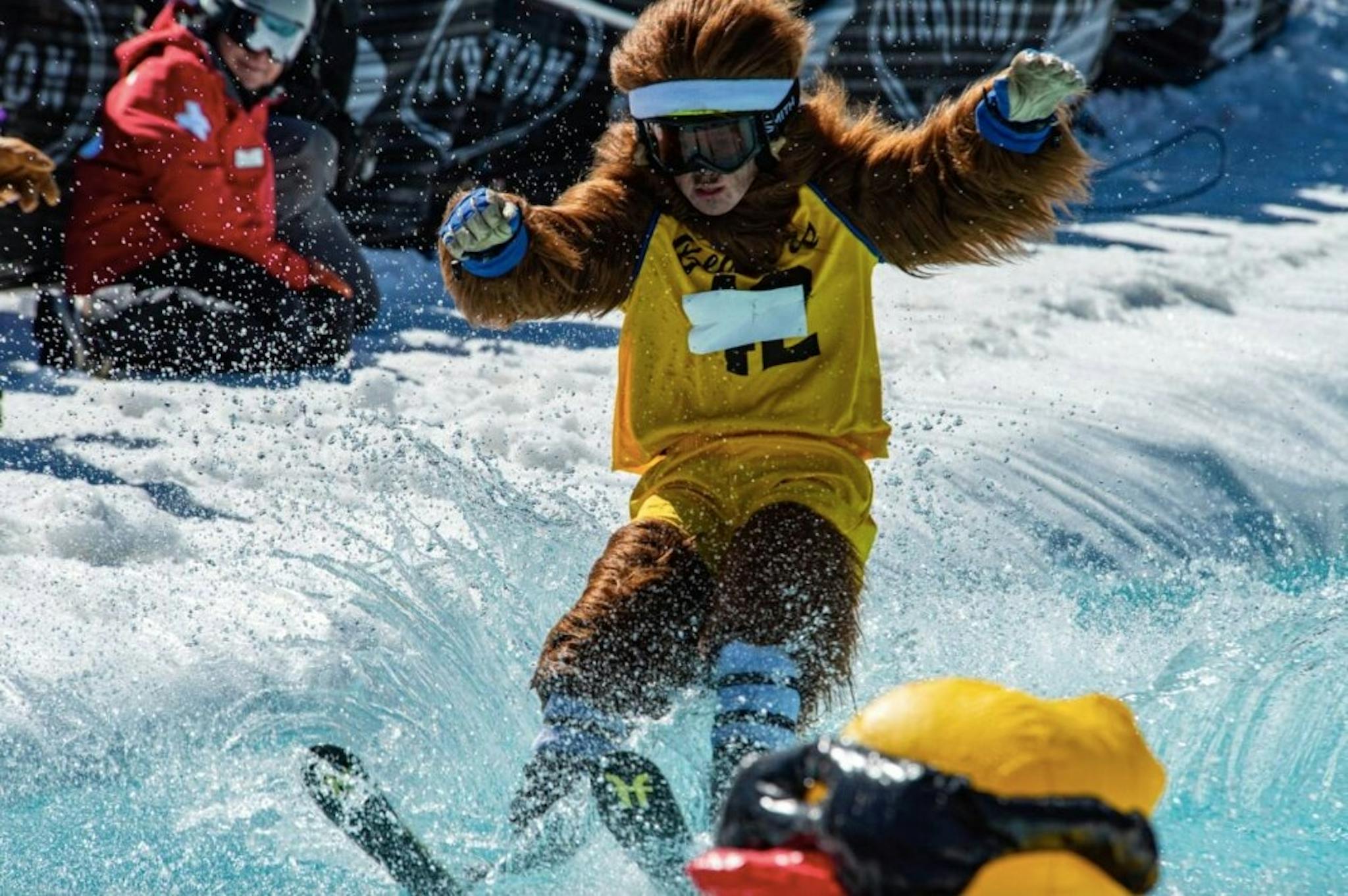 Skier in a bear costume splashing water in a pond skim event