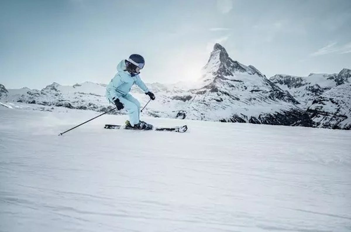 skier on a groomed slope with beautiful snowy mountain backdrop