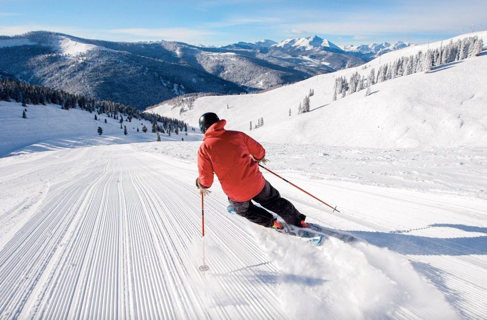 person skiing down a freshly groomed run on a sunny day at Vail