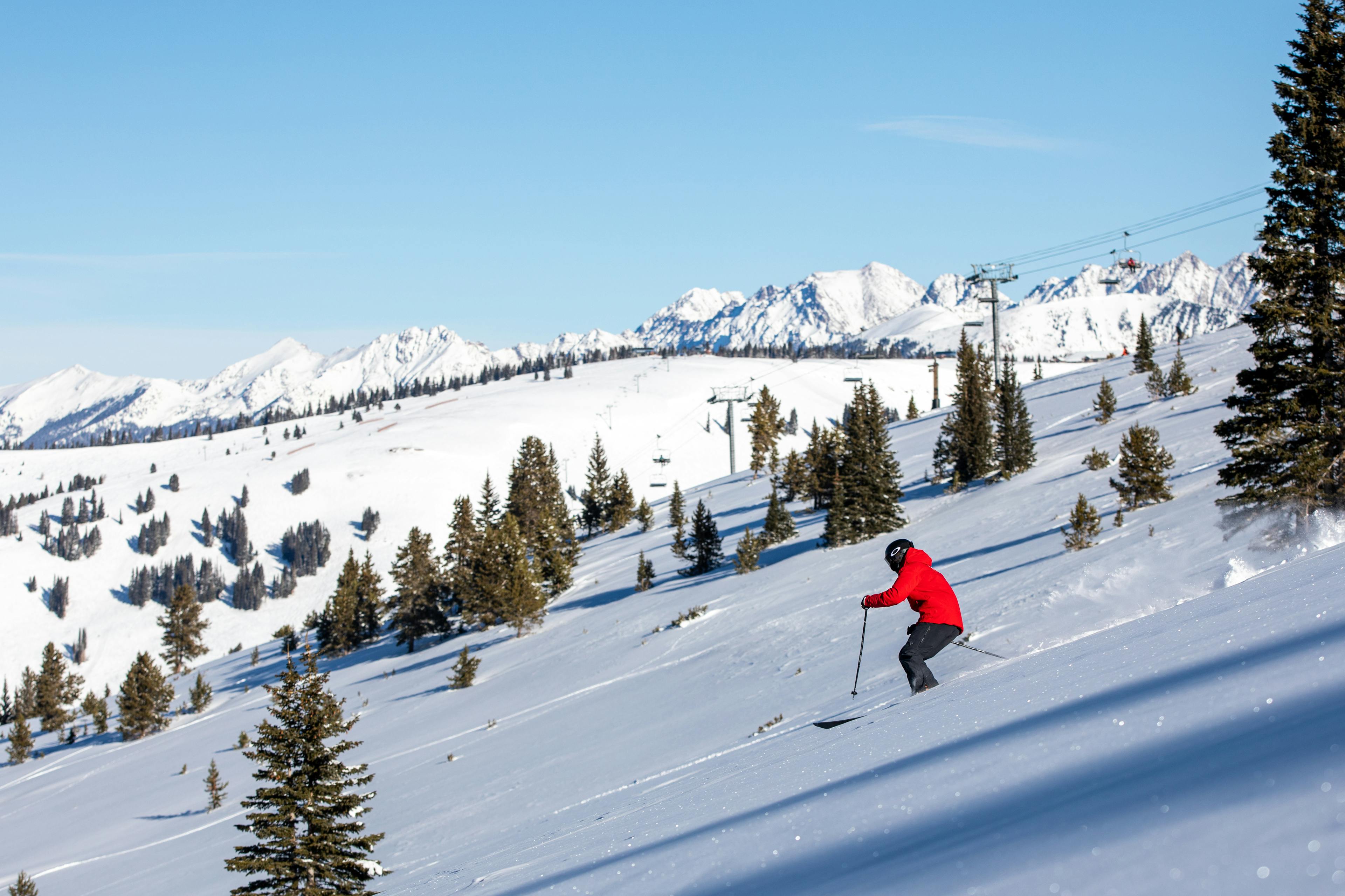 Man in orange ski jacket skiing at Vail