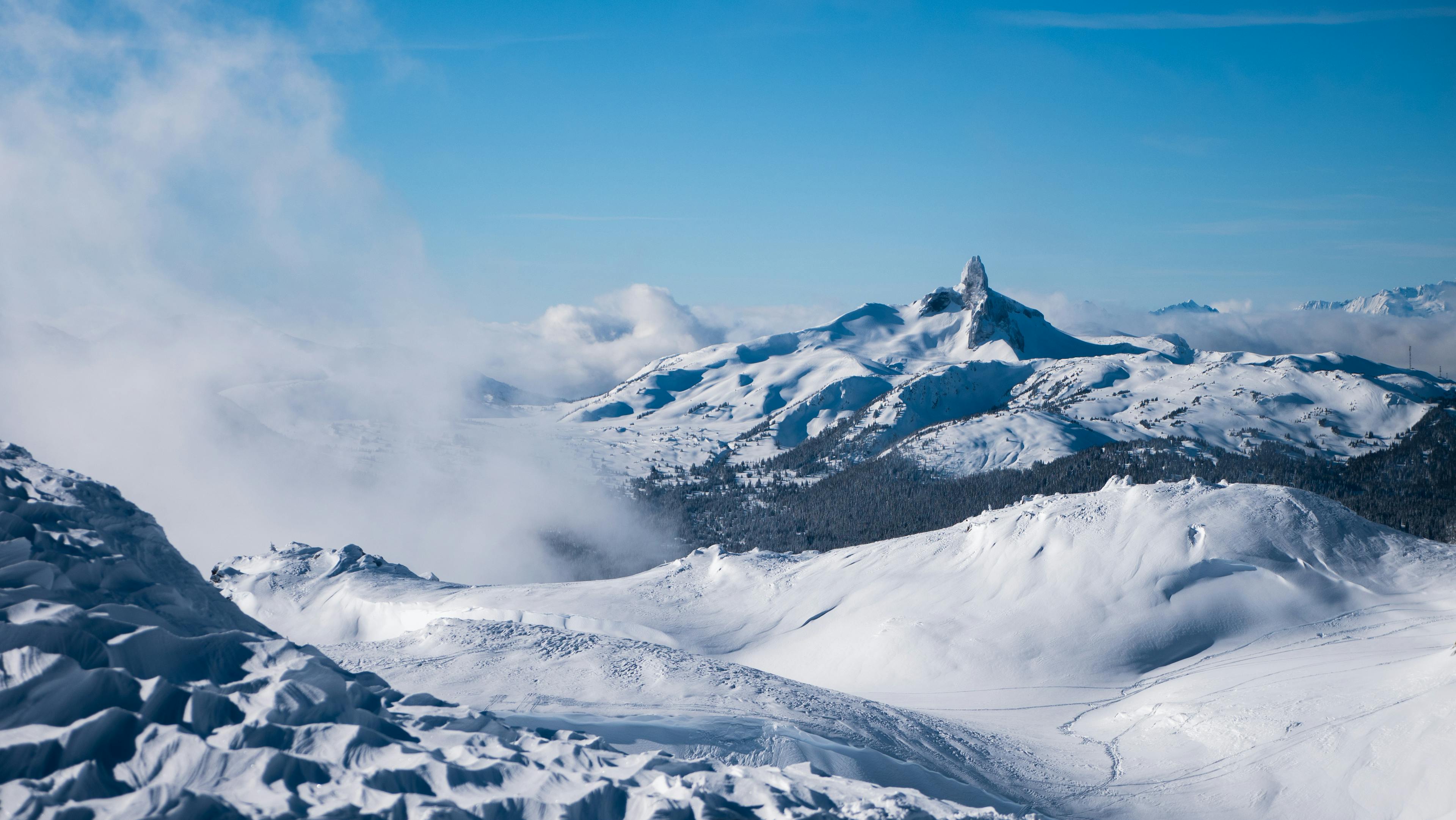 wide scale image of Whistler Blackcomb Ski Resort with blue skies and snow covered trails.