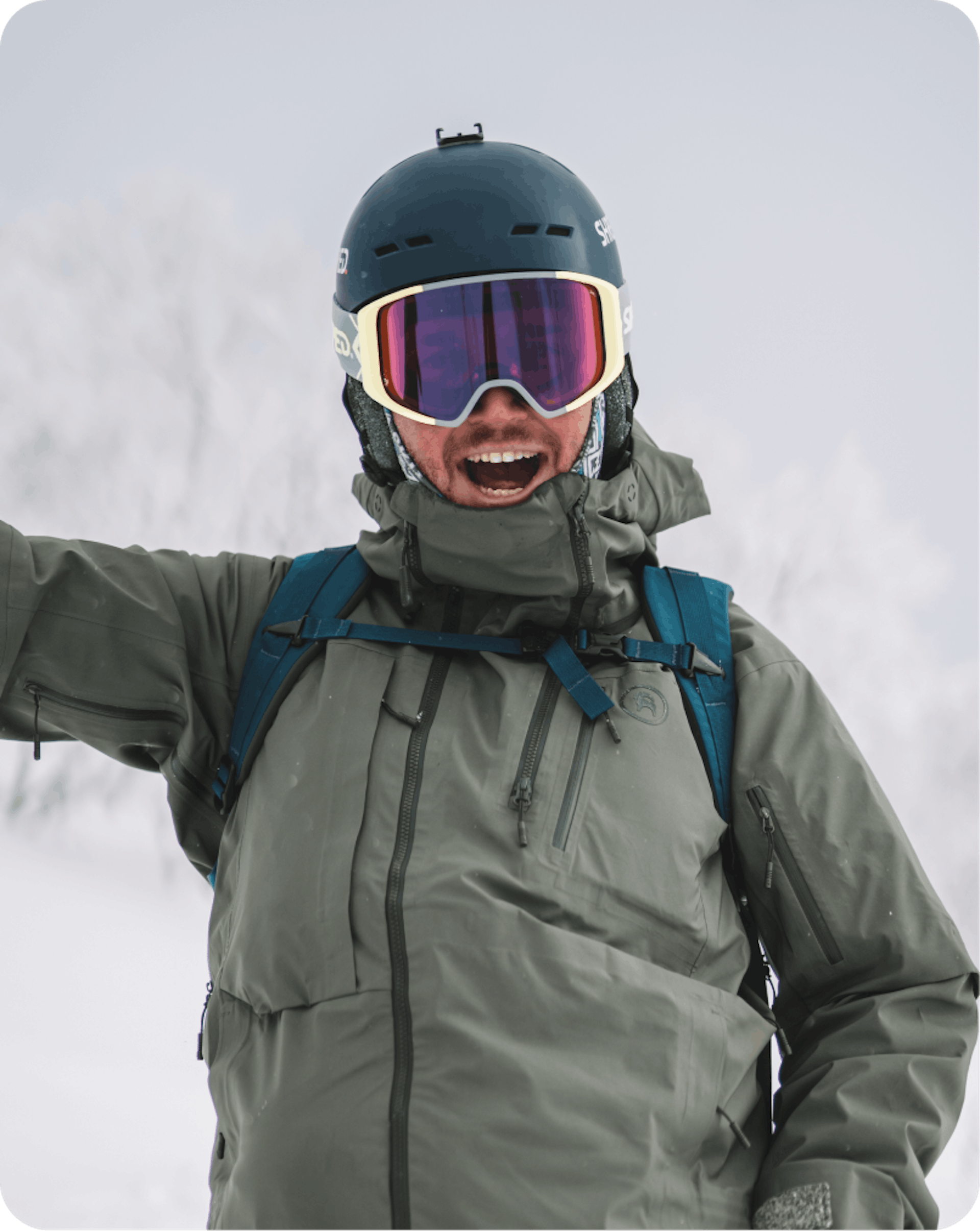 A man in a ski jacket and goggles raises his hand, ready for an adventure on the slopes.