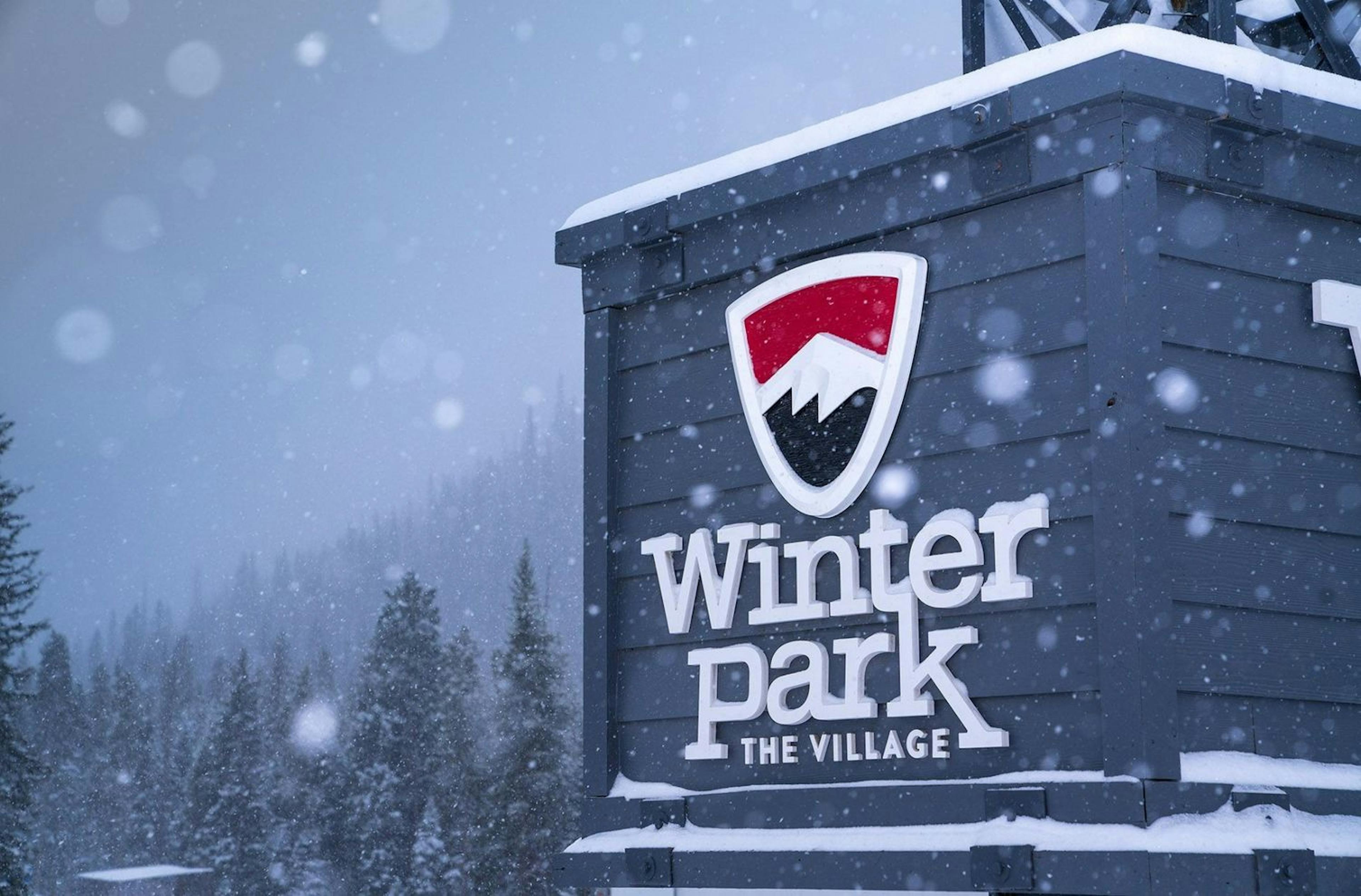 Snow falling on the village sign at Winter Park Resort