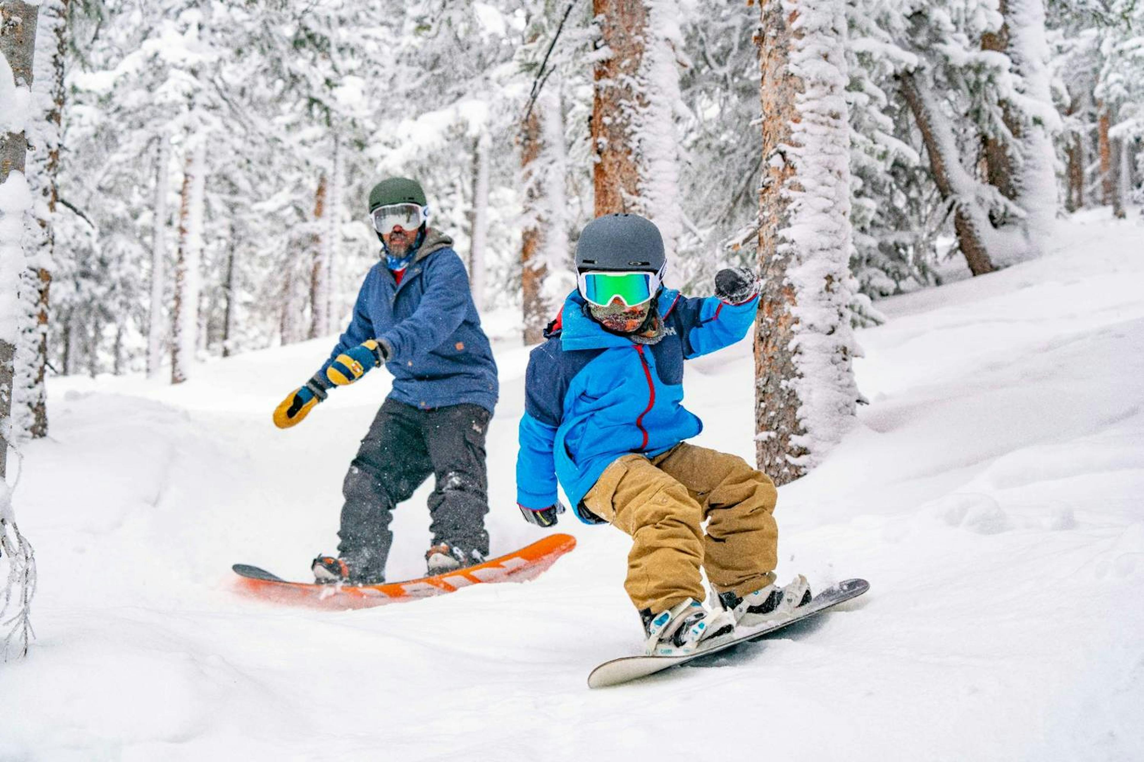 Father and Son riding snowboards through the trees at Keystone Resort