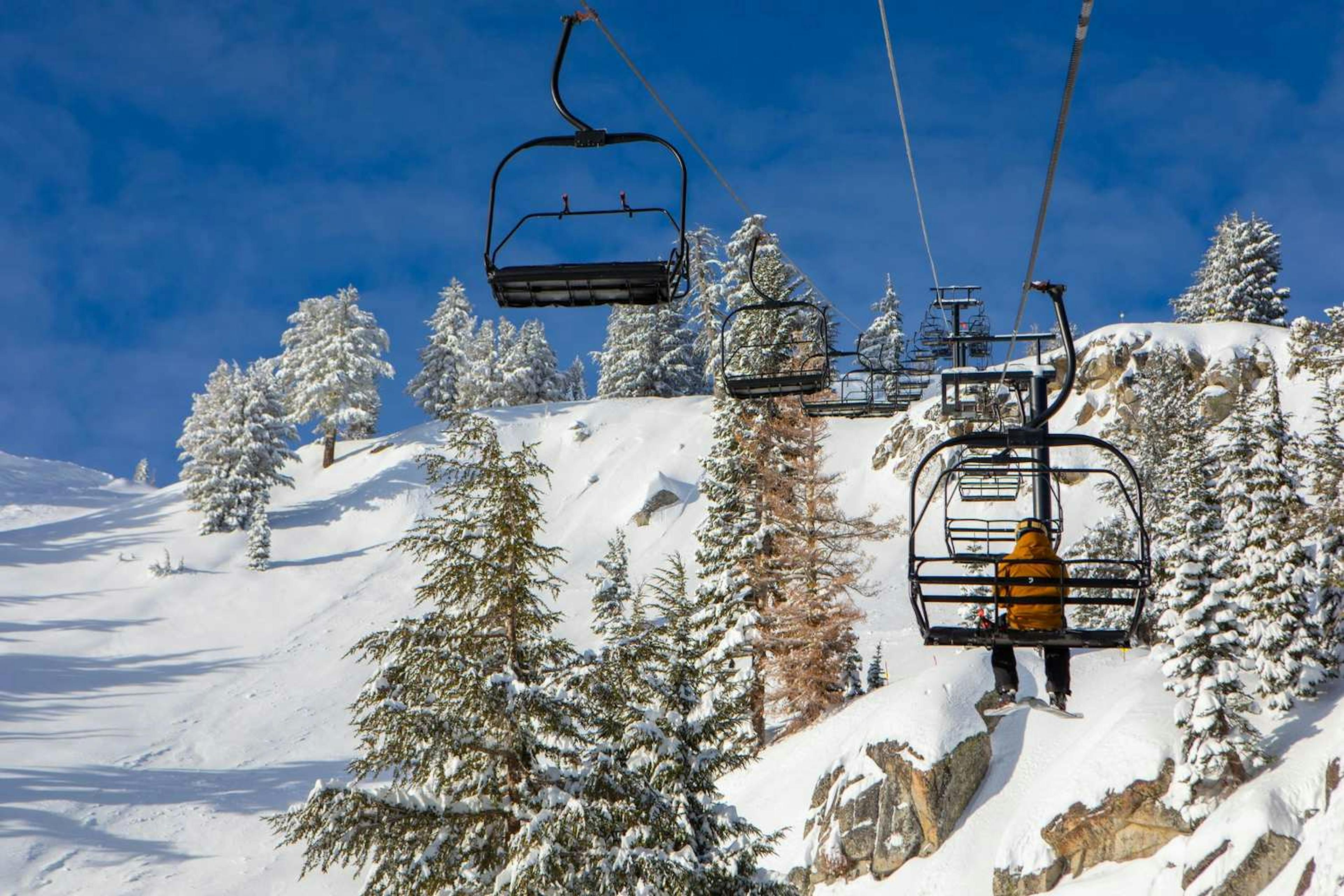 Lone skier on the chairlift above Granite Chief Peak at Palisades Tahoe