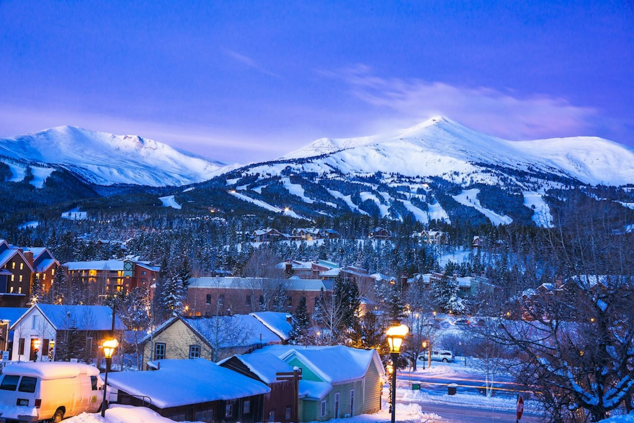 Twighlight shot of the town of breckenridge with snowcovered peaks in the distance