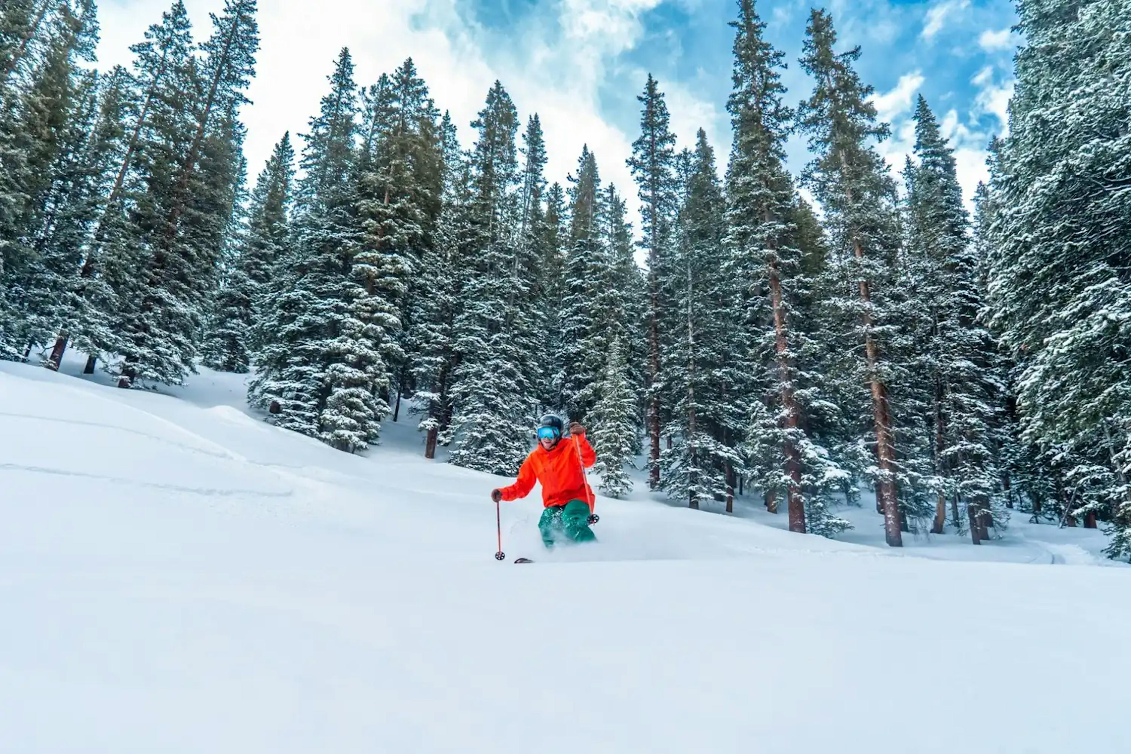 skier in a red jacket on the mountain at Winter Park Ski Resort.