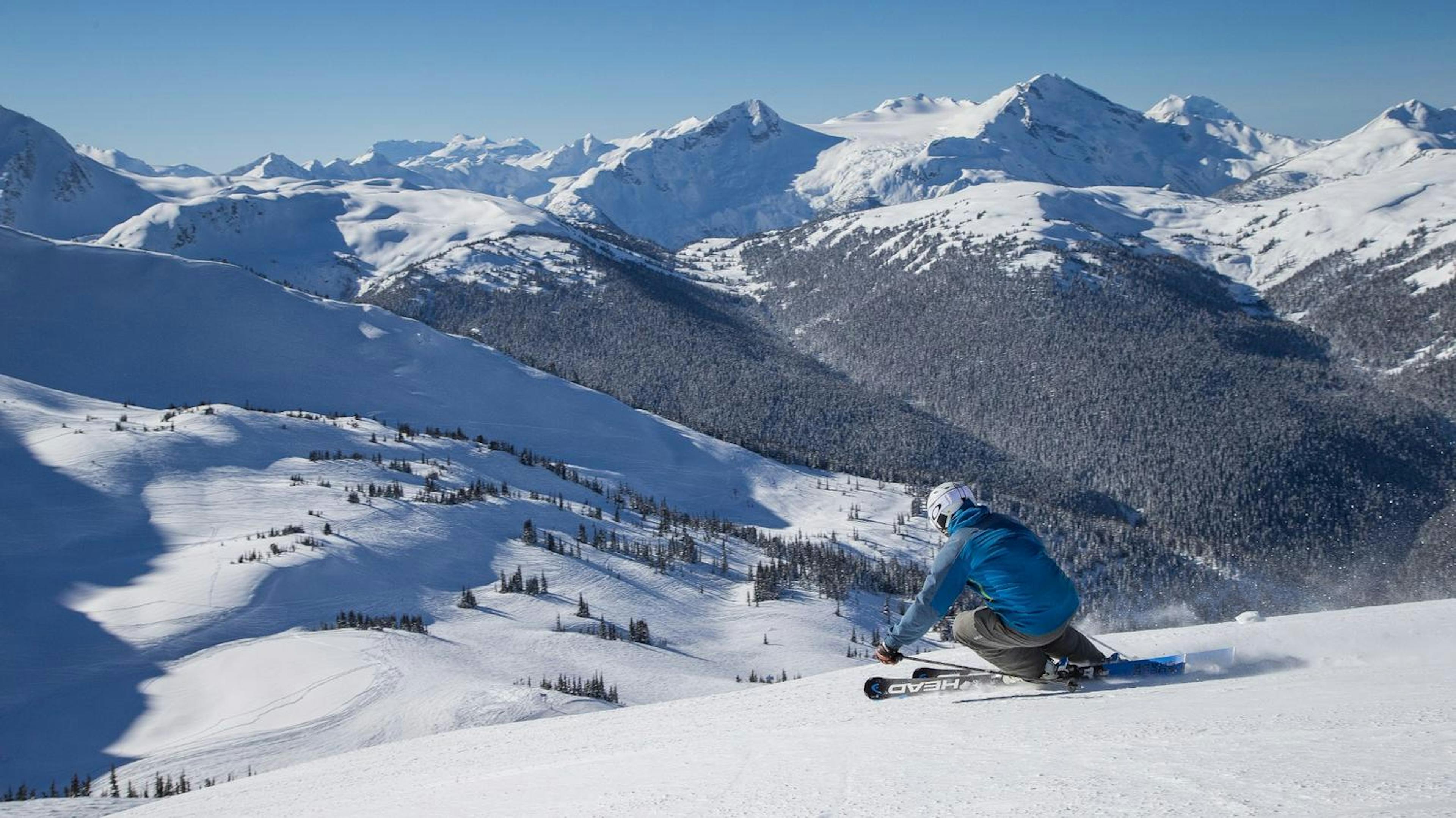 Skier of undiscernible gender in blue ski jacket skiing 7th Heaven at Whistler Blackcomb in British Columbia, Canada.