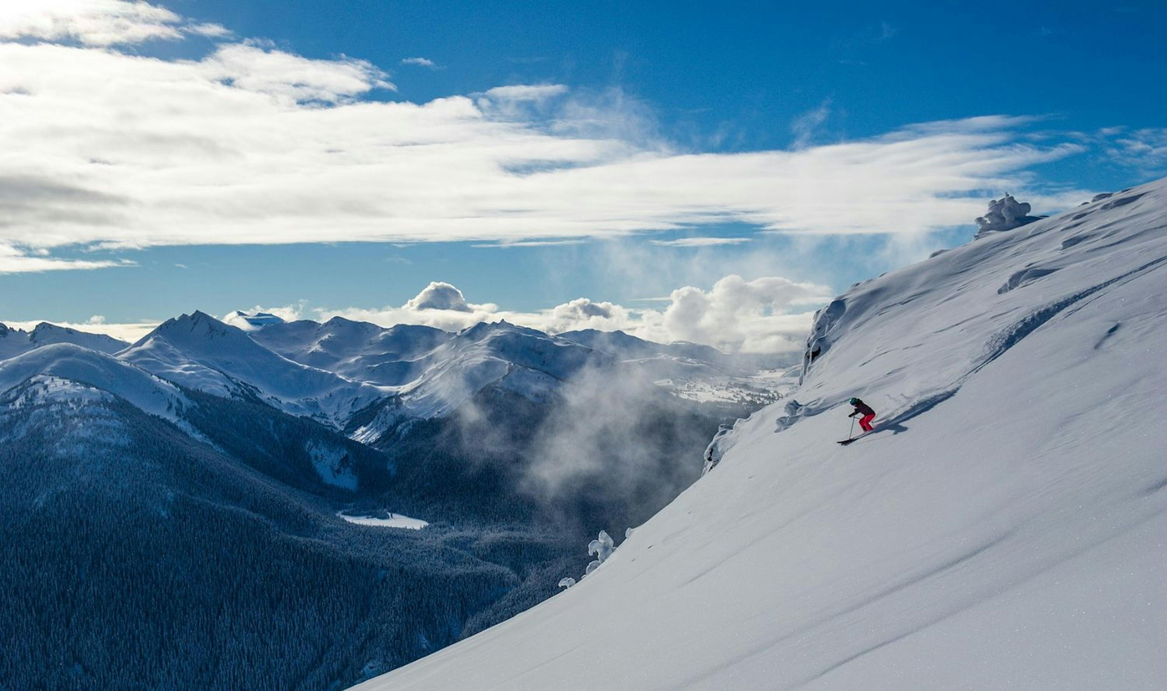 Skier of undiscernible gender in pink ski trousers enjoying downhill skiing at Whistler Blackcomb in British Columbia, Canada.