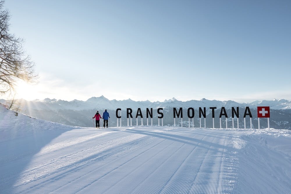 Crans-Montana ski resort with sun rising behind the mountain peaks.