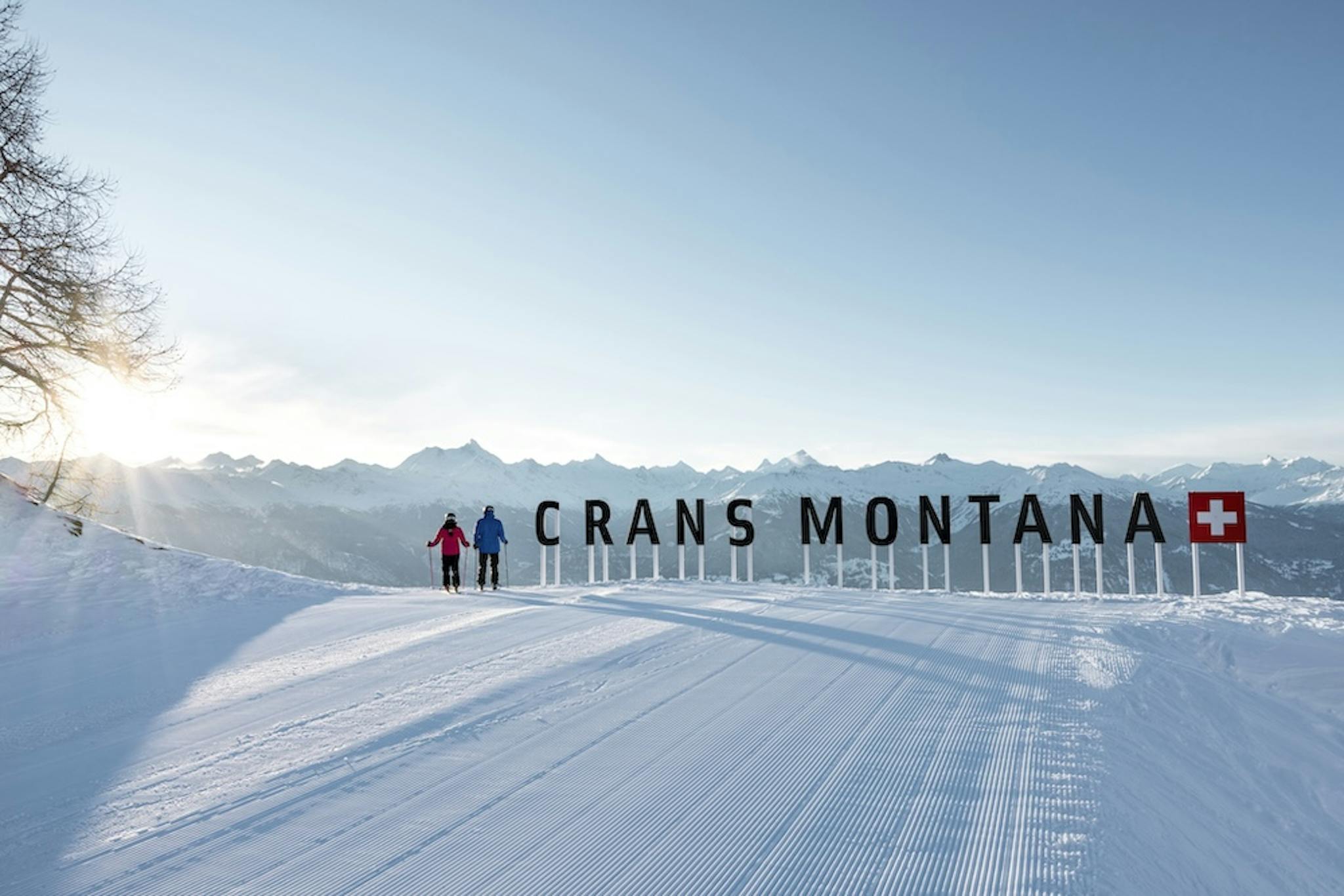 Crans-Montana ski resort with sun rising behind the mountain peaks.