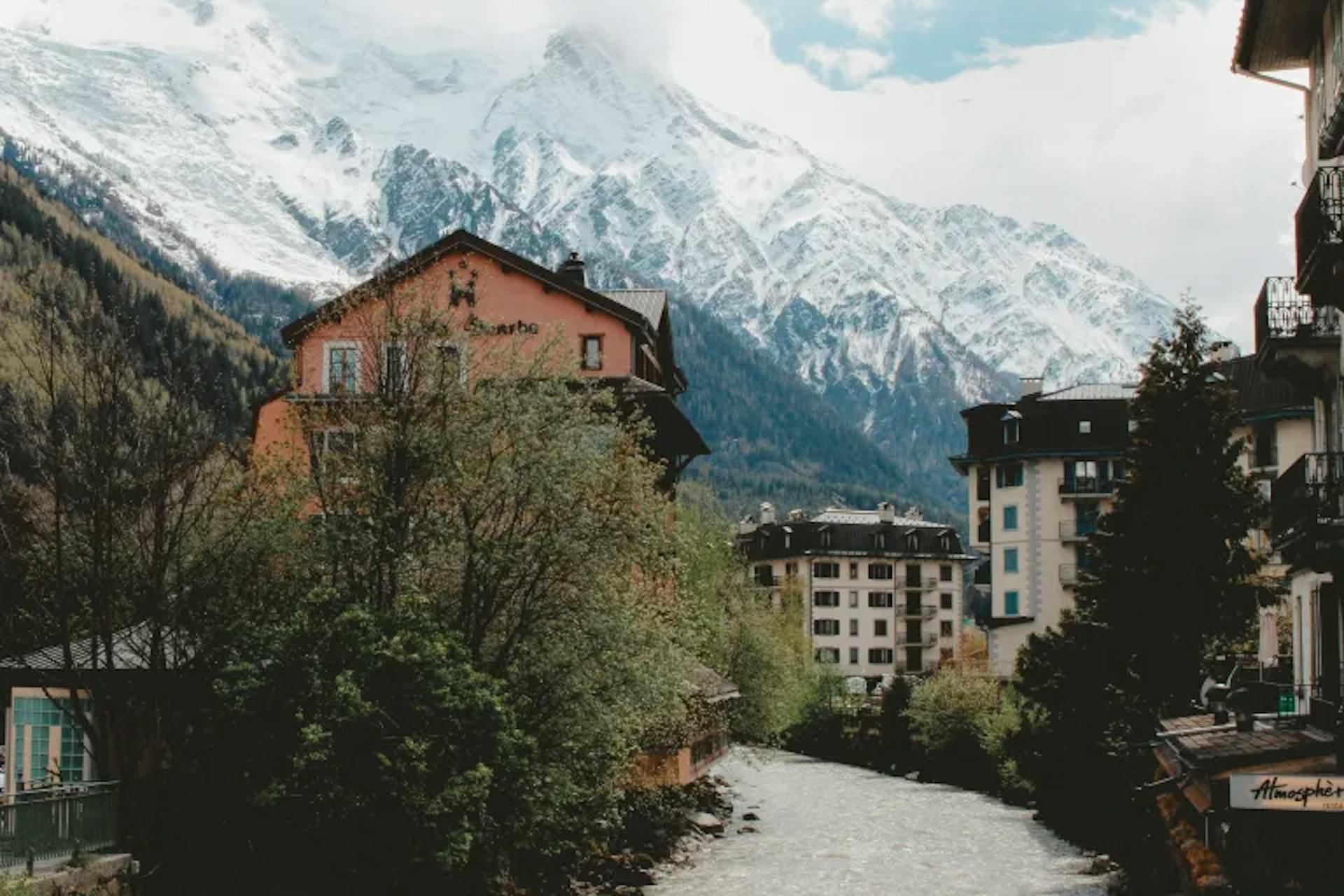 French village with snow-covered mountains in background.