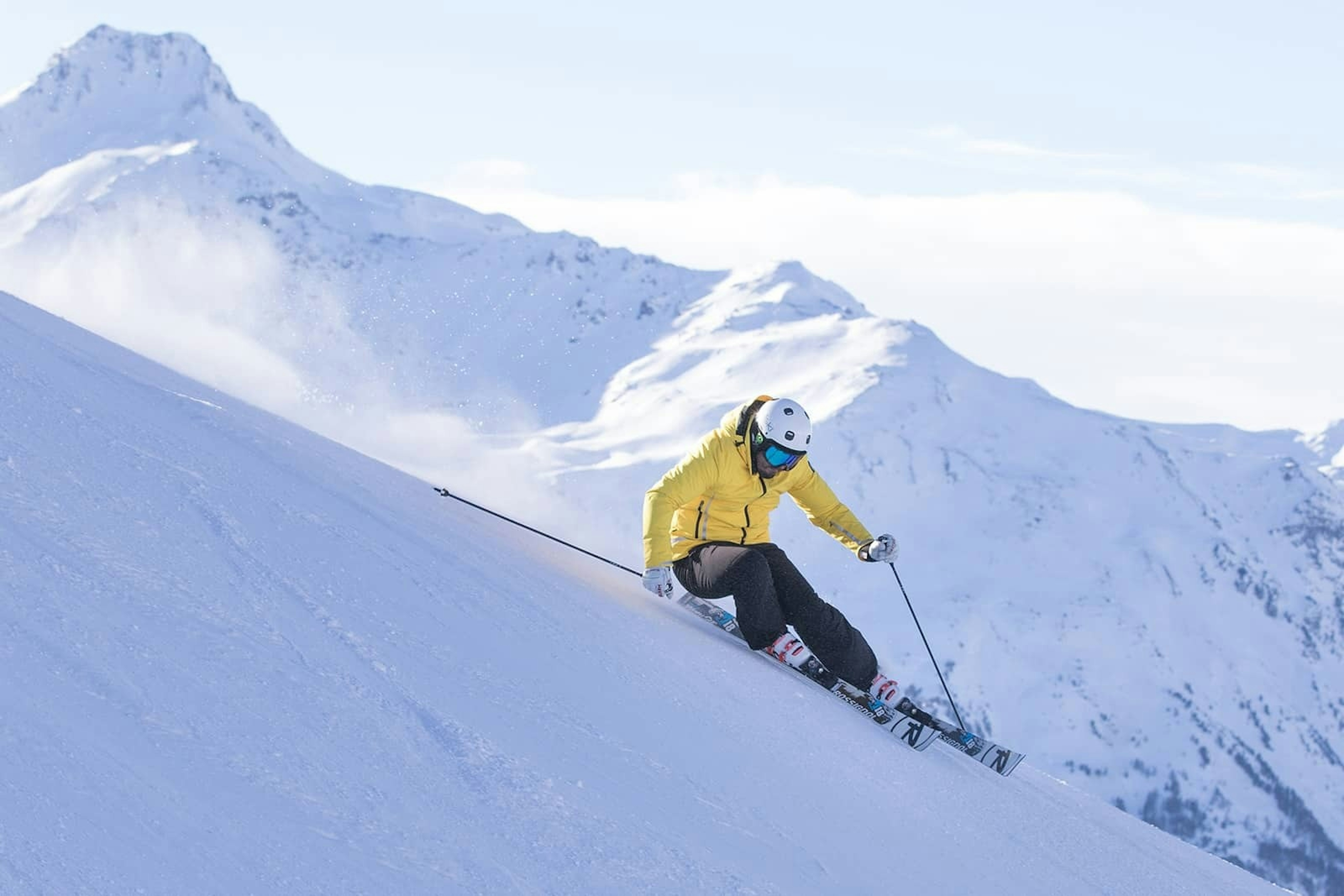 Male skier in yellow jacket skiing down the slopes of Bormio