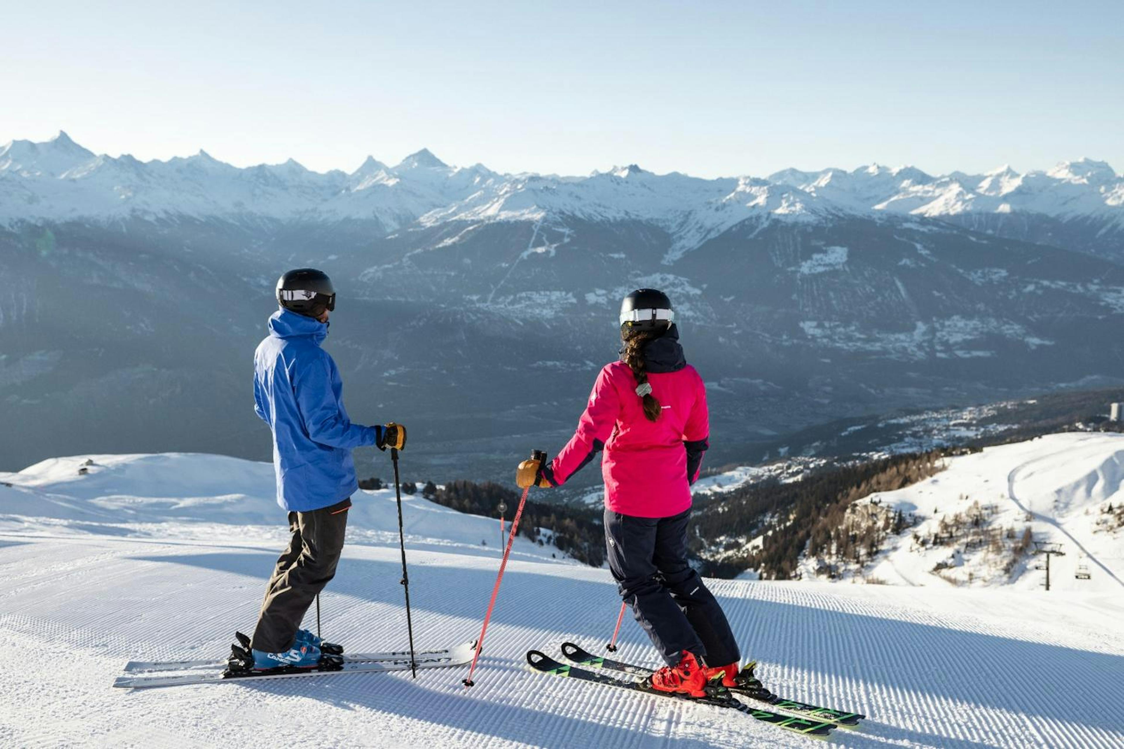 Skiers stopped at top of groomed ski run at Crans-Montana.