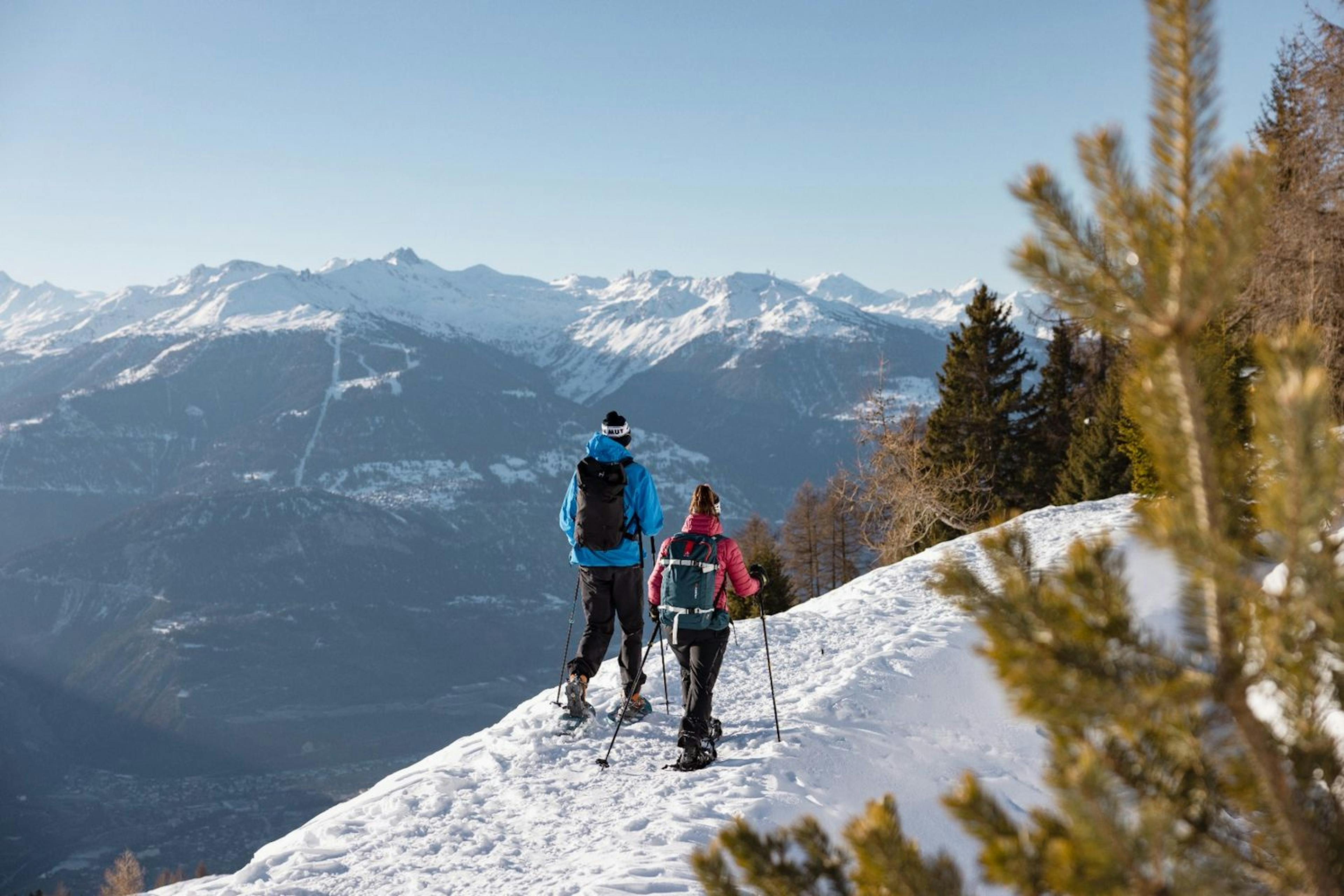 Two people snowshoeing in Crans-Montana. 