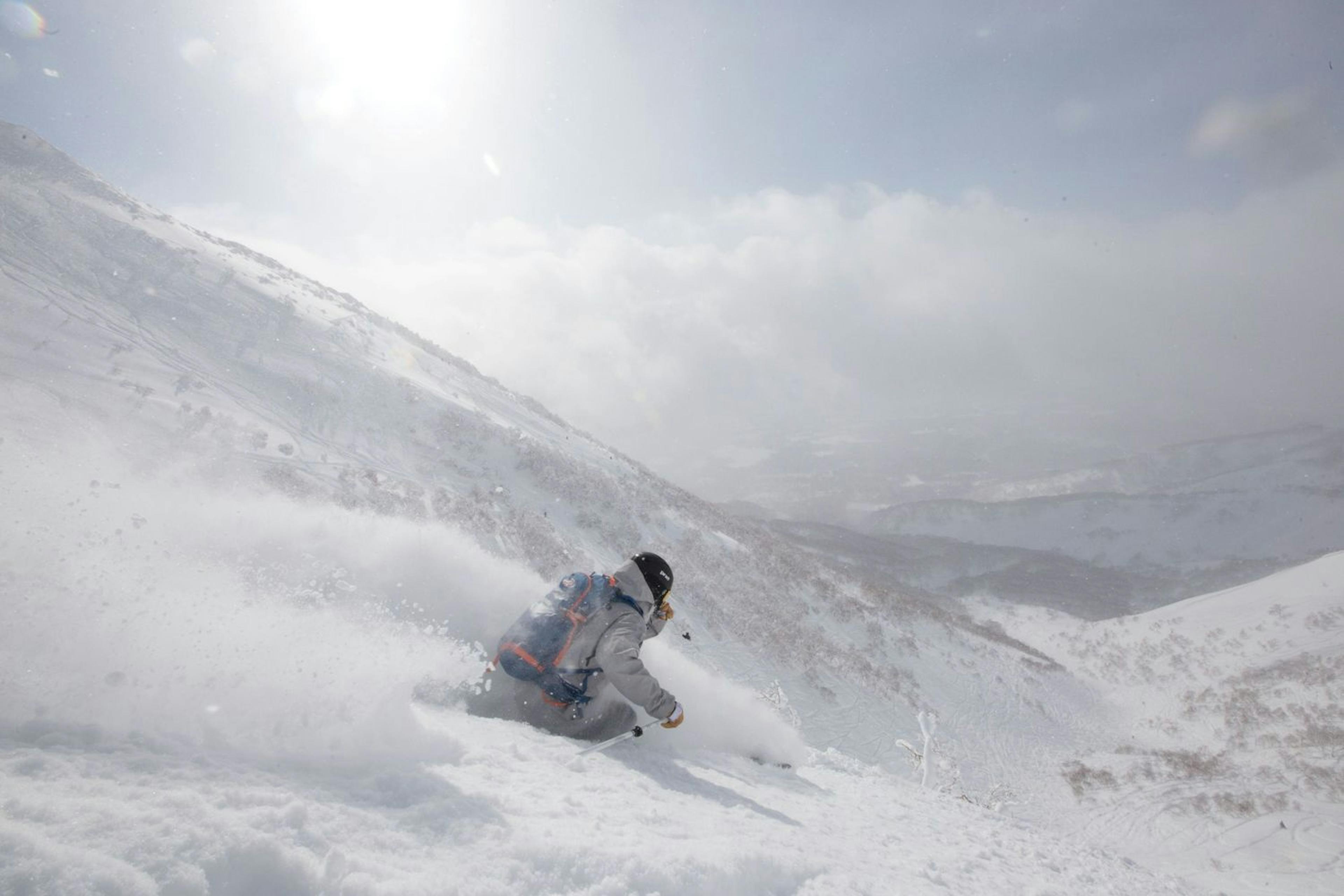 A skierexpertly navigates a snowy slope in bright, sunny conditions.