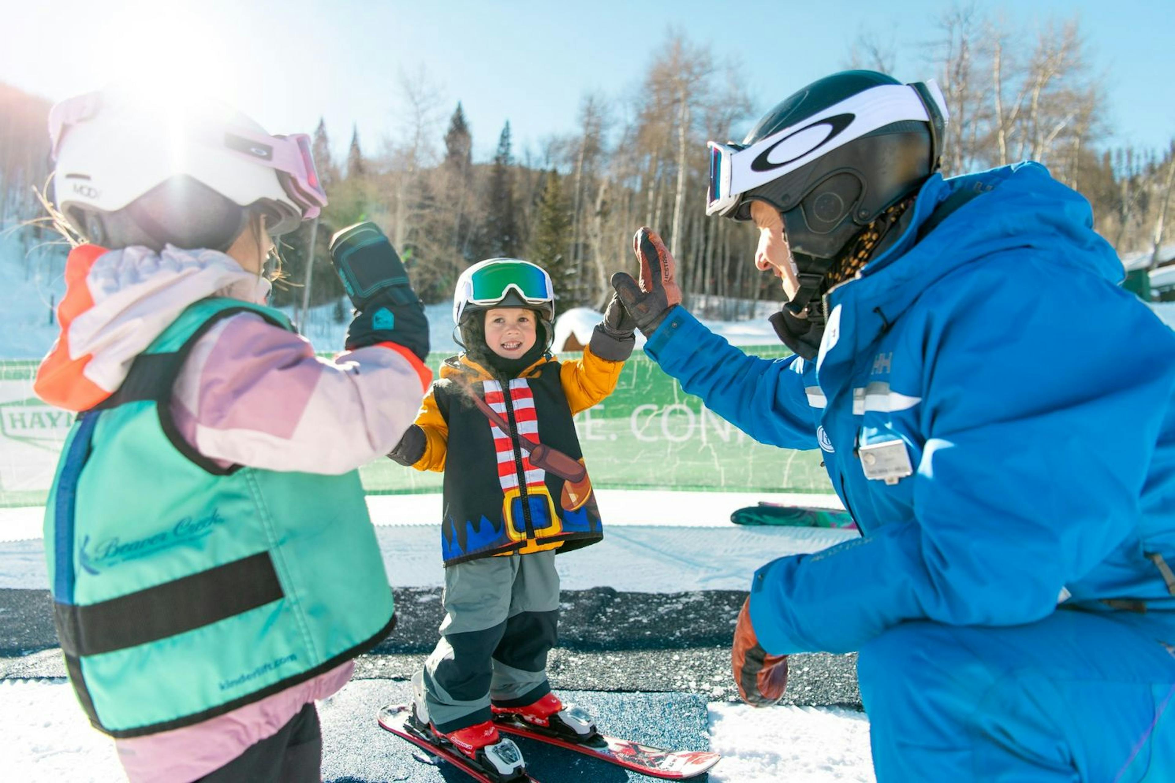 small children smile and high five their ski instructor at beaver creek resort