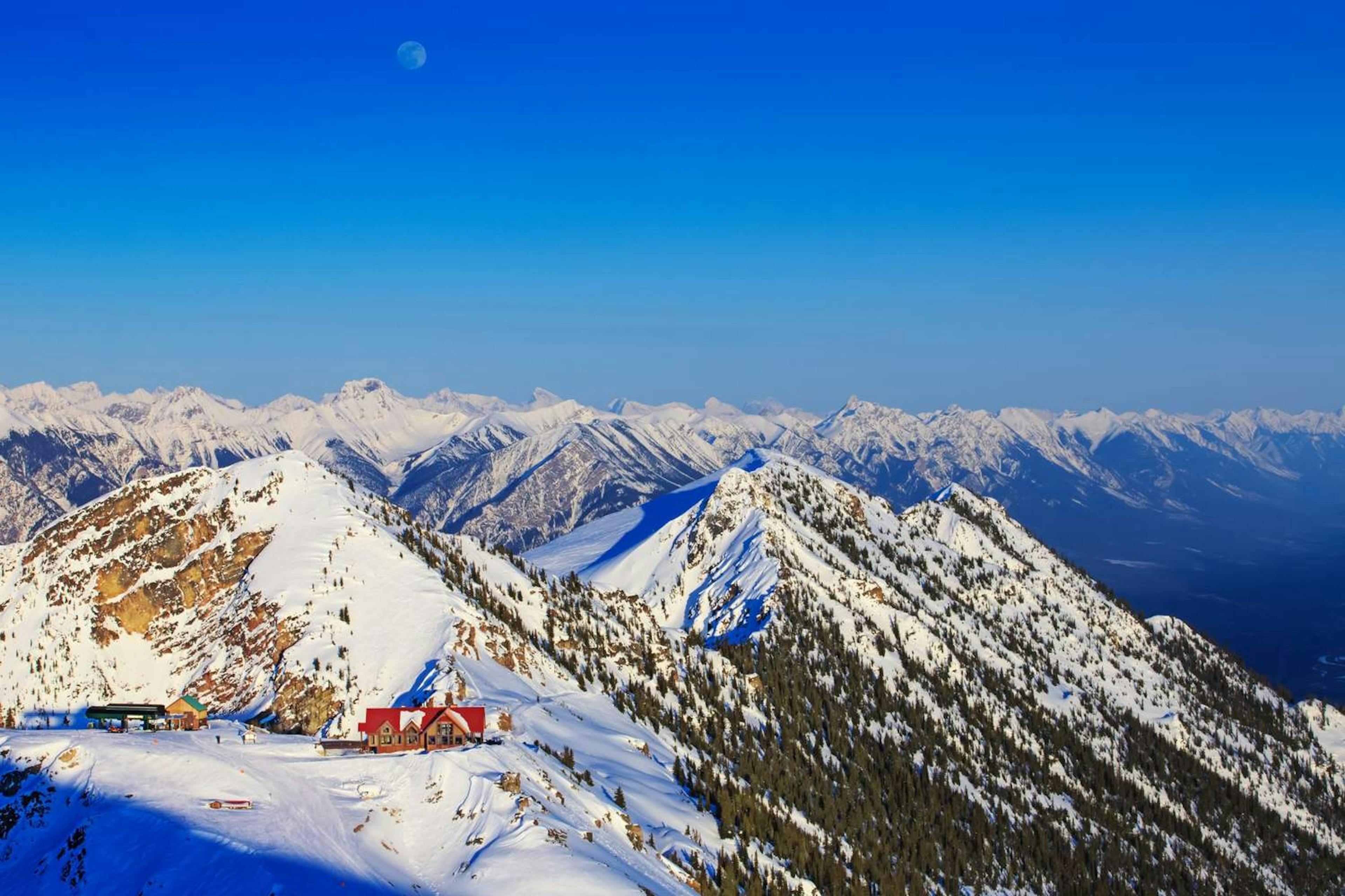 A cozy ski lodge perched atop Kicking Horse Mountain, surrounded by stunning snow-covered peaks.