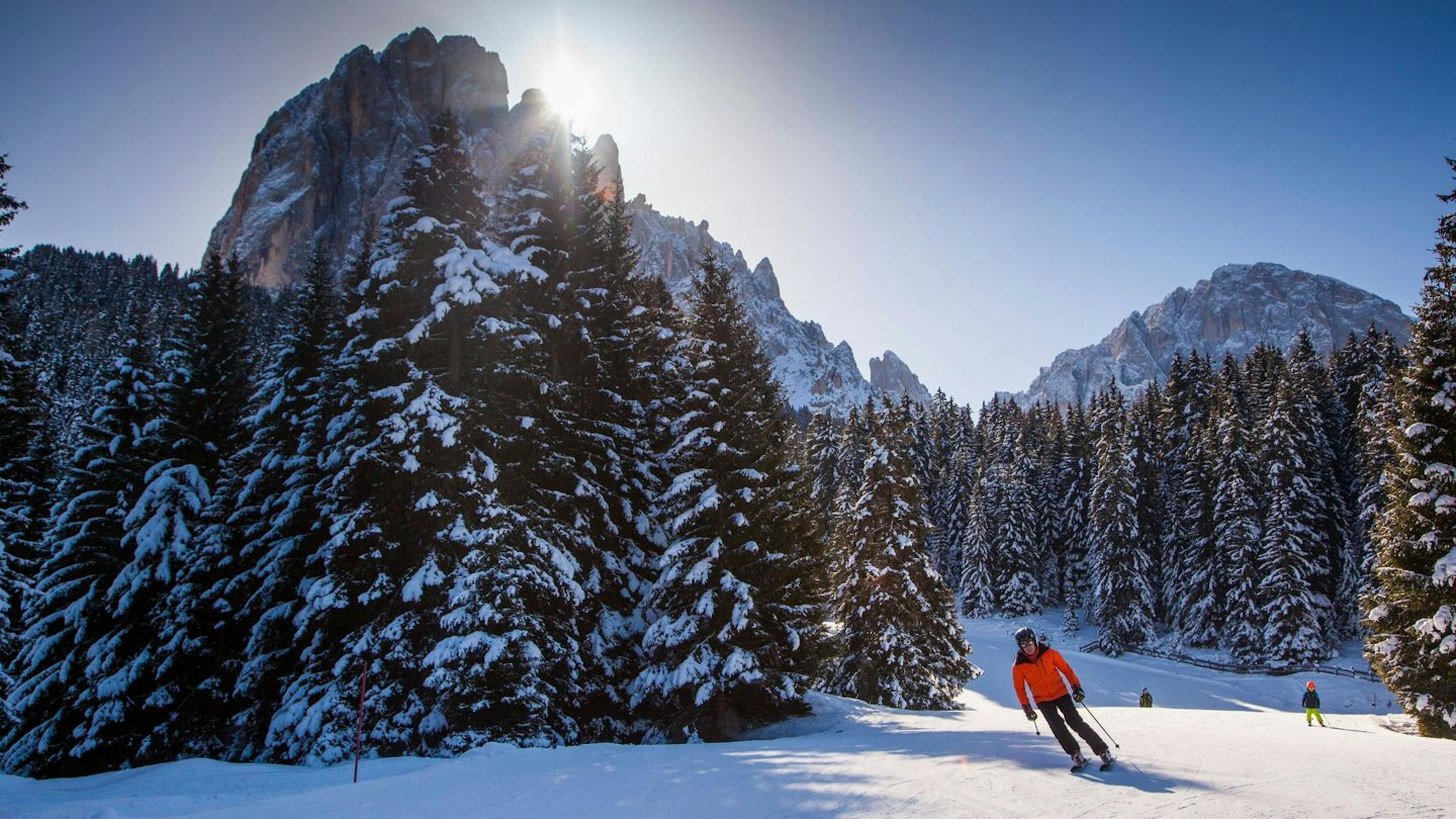 Skier in orange jacket skiing Val Gardena in the afternoon