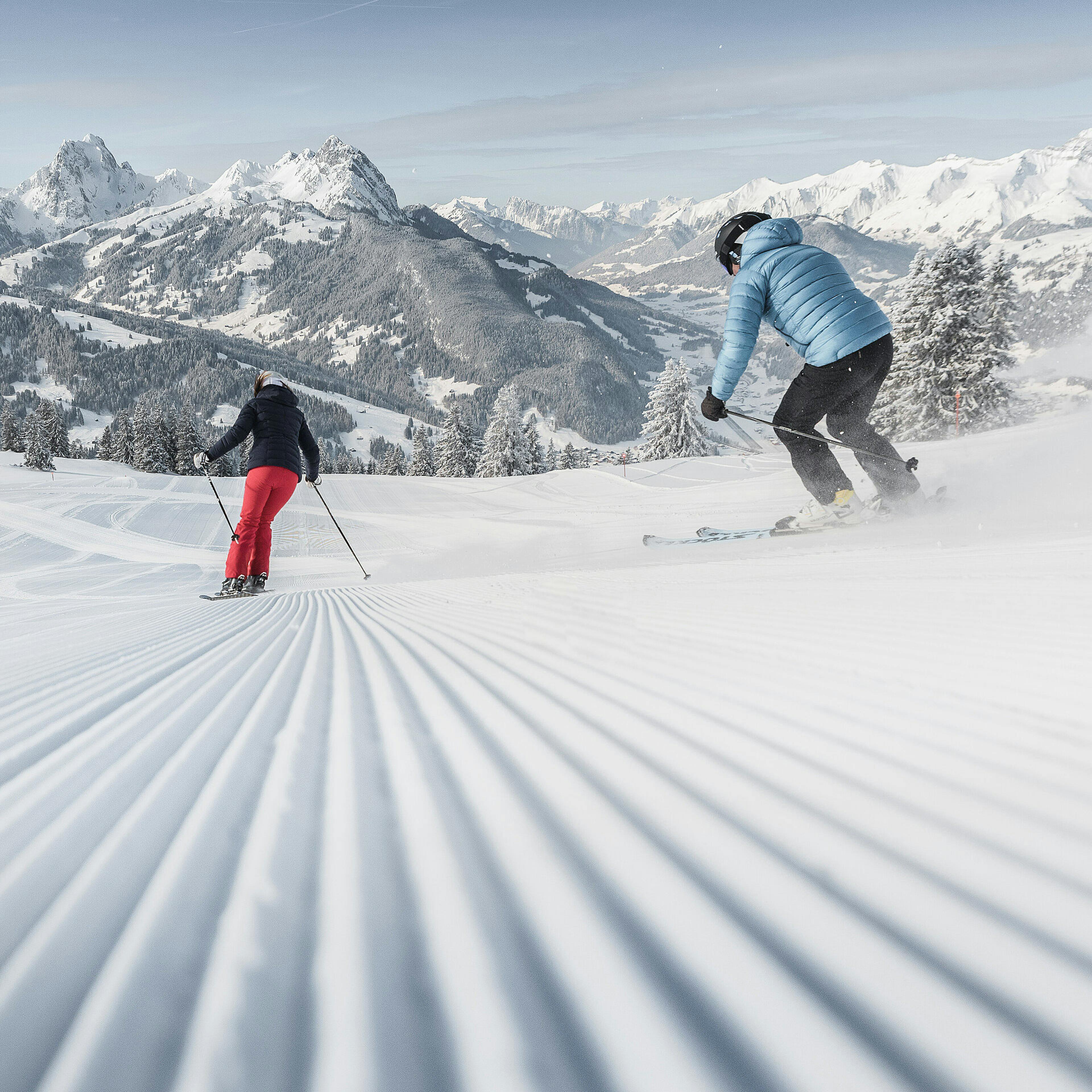 Two skiers skiing fresh corduroy in Gstaad, Switzerland 